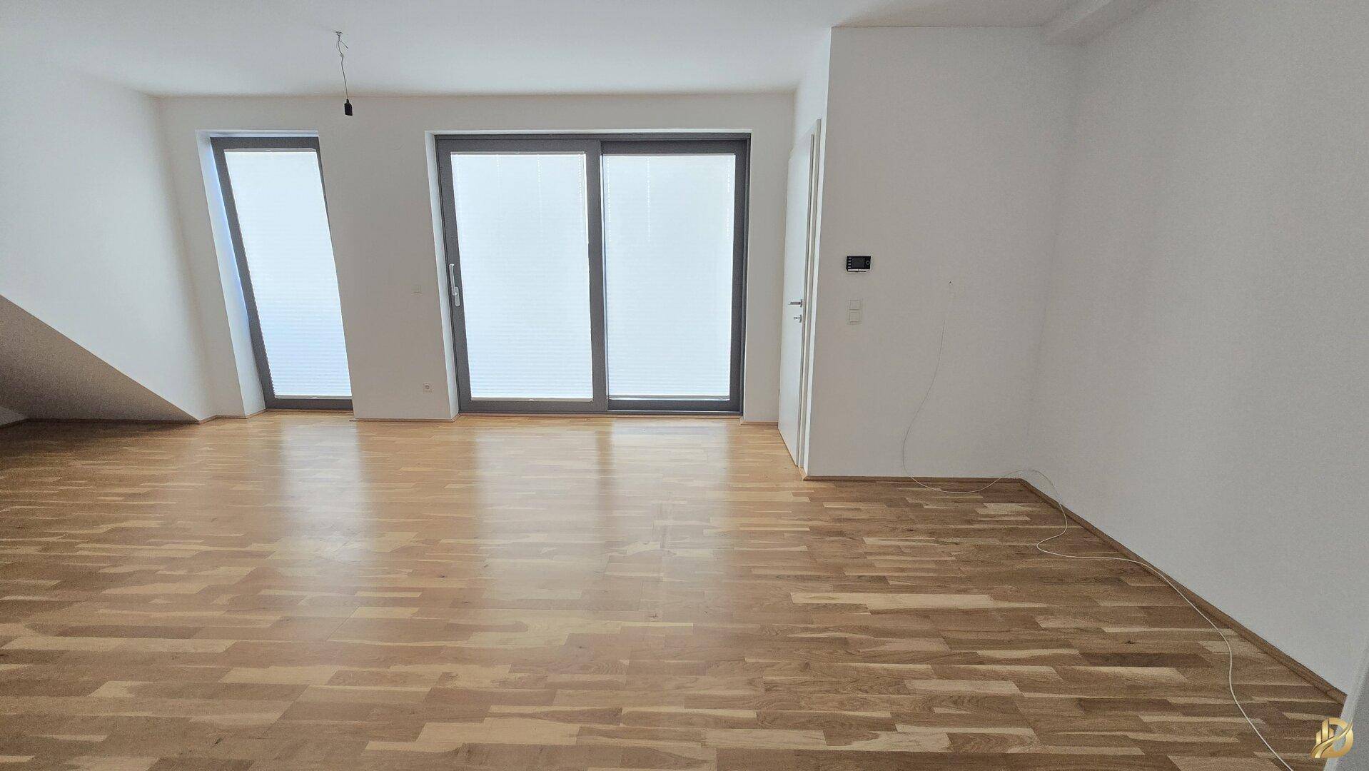 Geräumiges Wohnzimmer mit großen Fenstern und Holzboden, bereit zur individuellen Einrichtung.