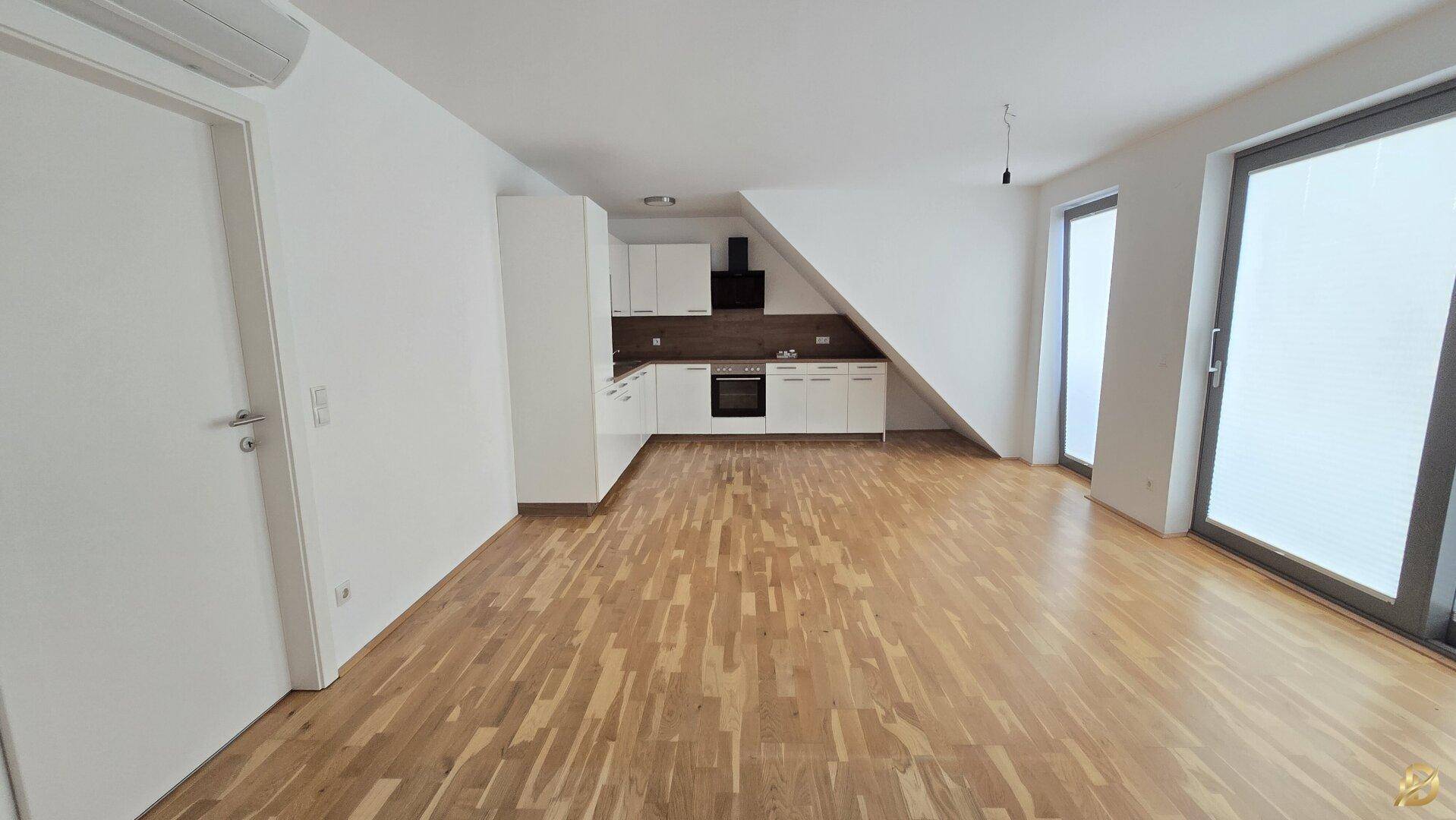 Heller Wohnbereich mit offener Küche und Dachschräge, ideal für modernes und gemütliches Wohnen.