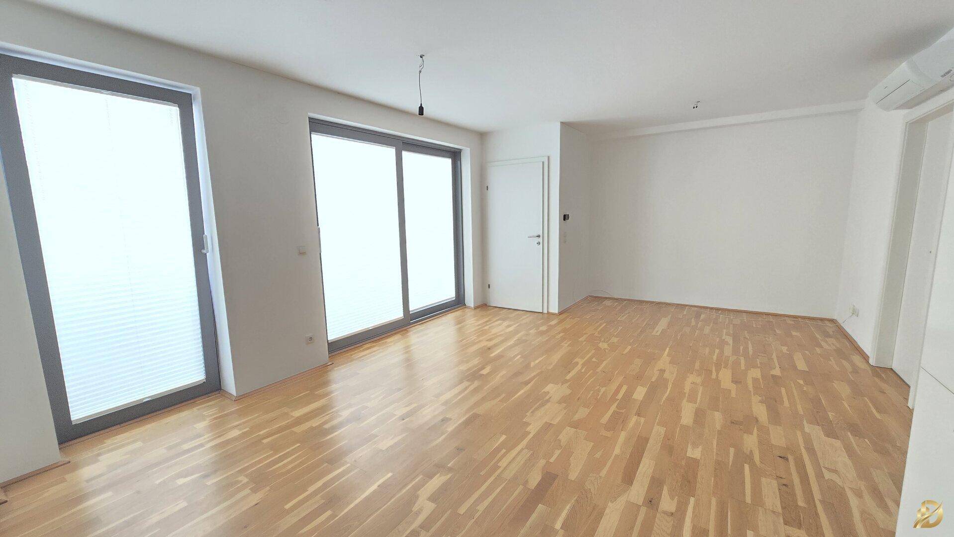 Lichtdurchflutetes Wohnzimmer mit Holzboden und Zugang zu einem Außenbereich, sehr einladend.