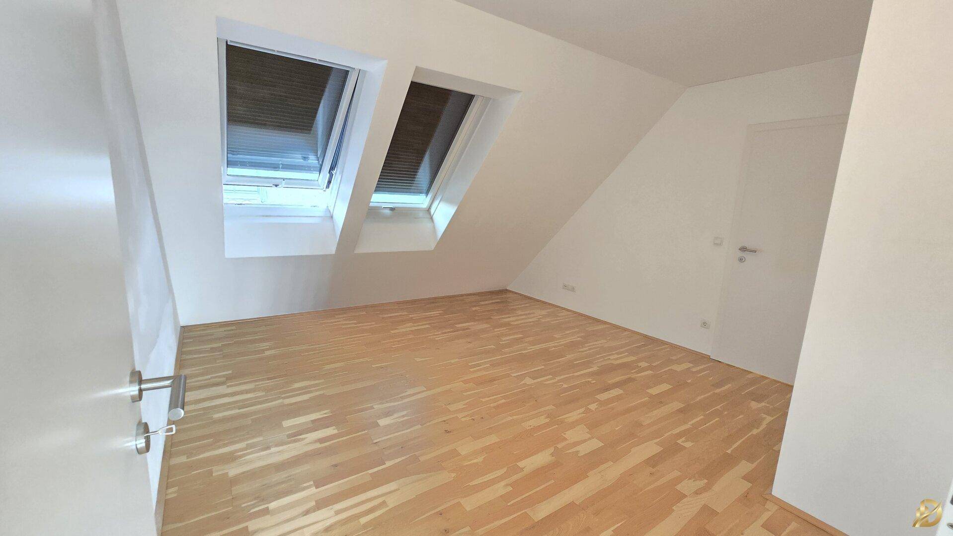 Schlafzimmer mit Holzboden und zwei Dachfenstern, schafft eine helle und freundliche Atmosphäre.
