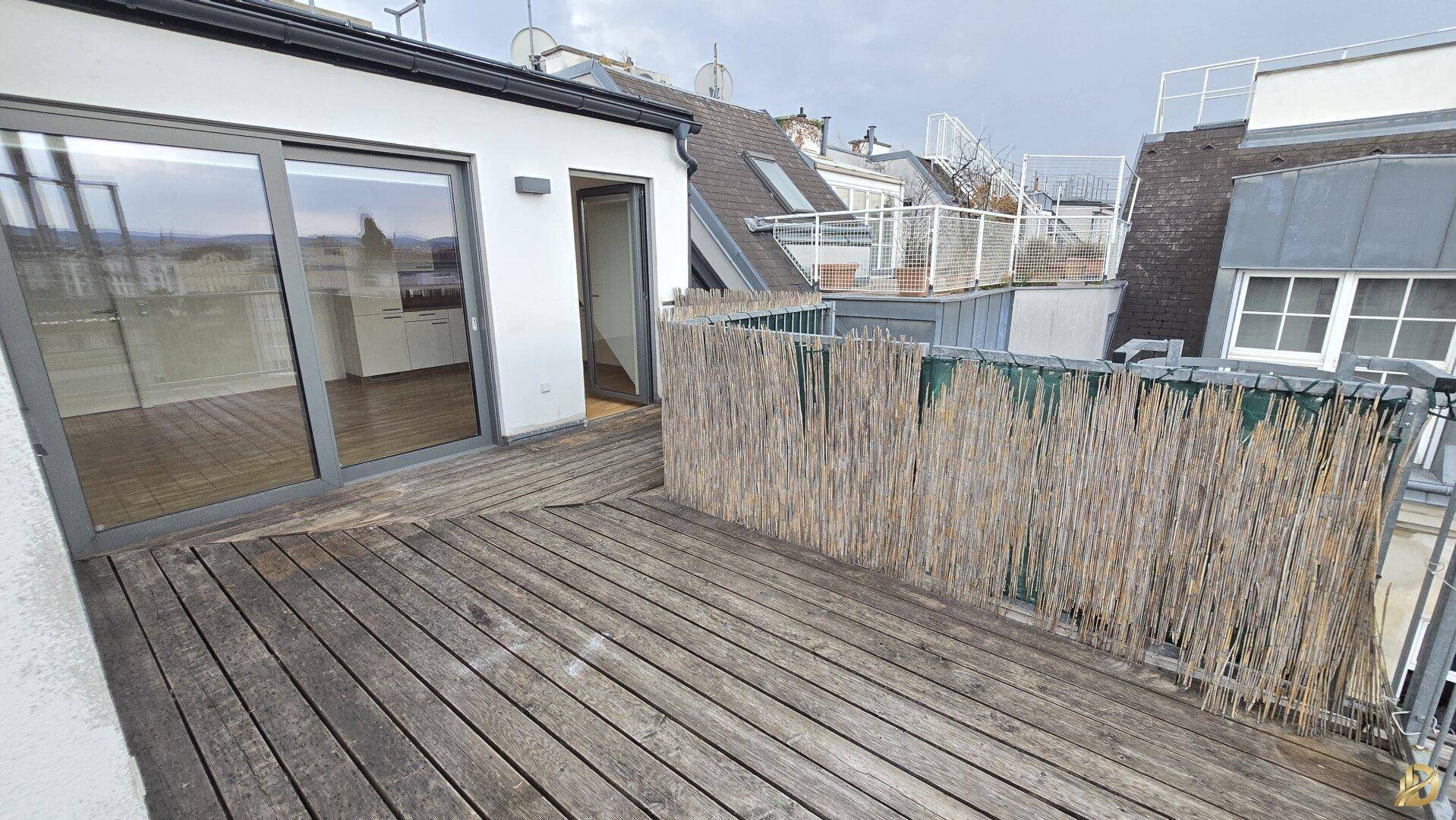 Geräumige Dachterrasse mit Holzboden und Blick über die Stadt, ideal zum Entspannen.
