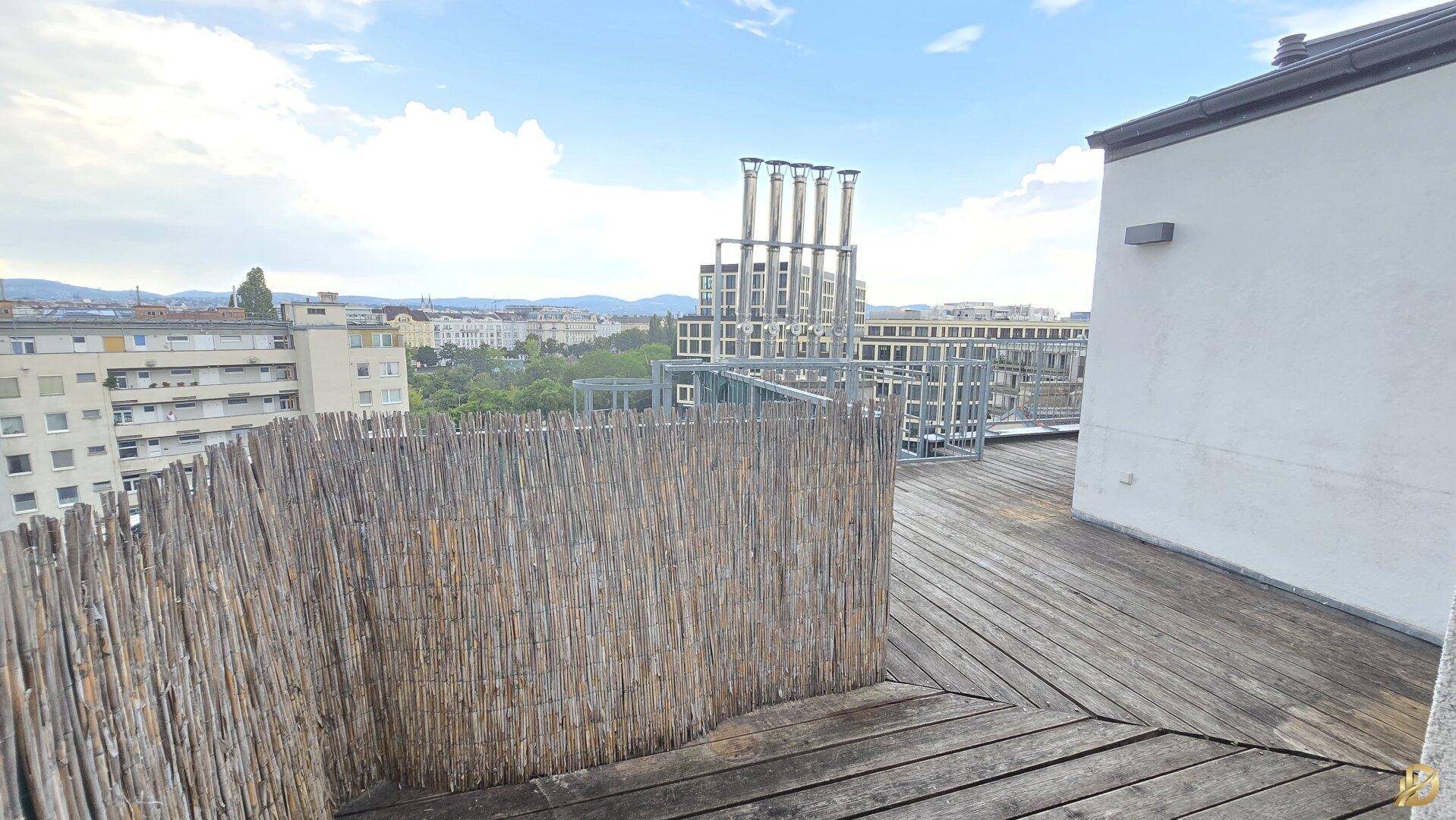 Weitläufige Dachterrasse mit Holzboden und Panoramablick auf die Stadt und Berge.