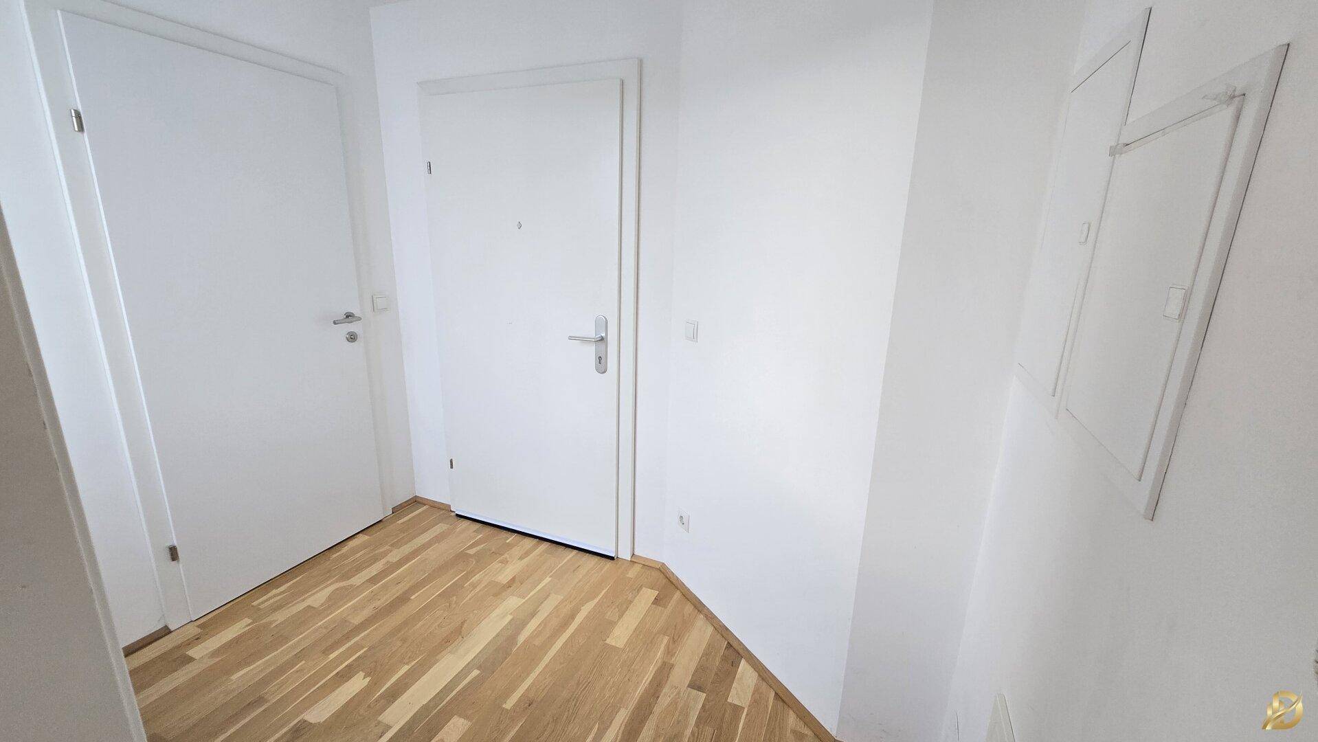 Eingangsbereich mit Holzboden und weißen Türen, bietet Zugang zu den Wohnräumen.