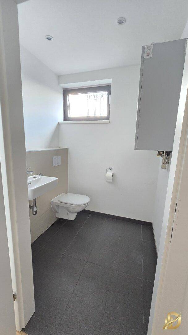 Separates Gäste-WC mit Fenster, wandhängendem WC und kleinem Waschbecken, sehr praktisch.