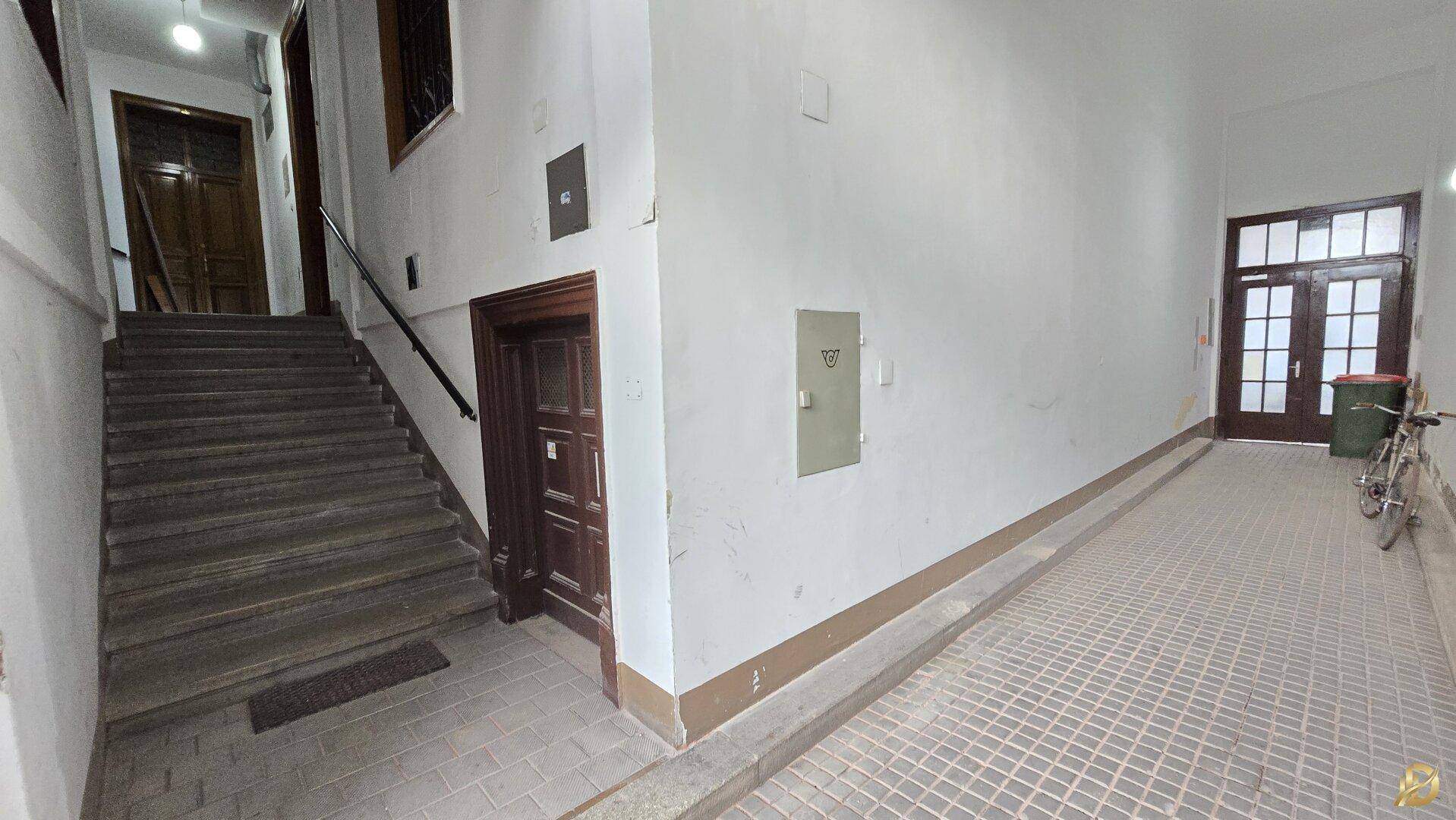 Eingangsbereich eines Mehrfamilienhauses mit Treppe und Rampe für verbesserte Barrierefreiheit.