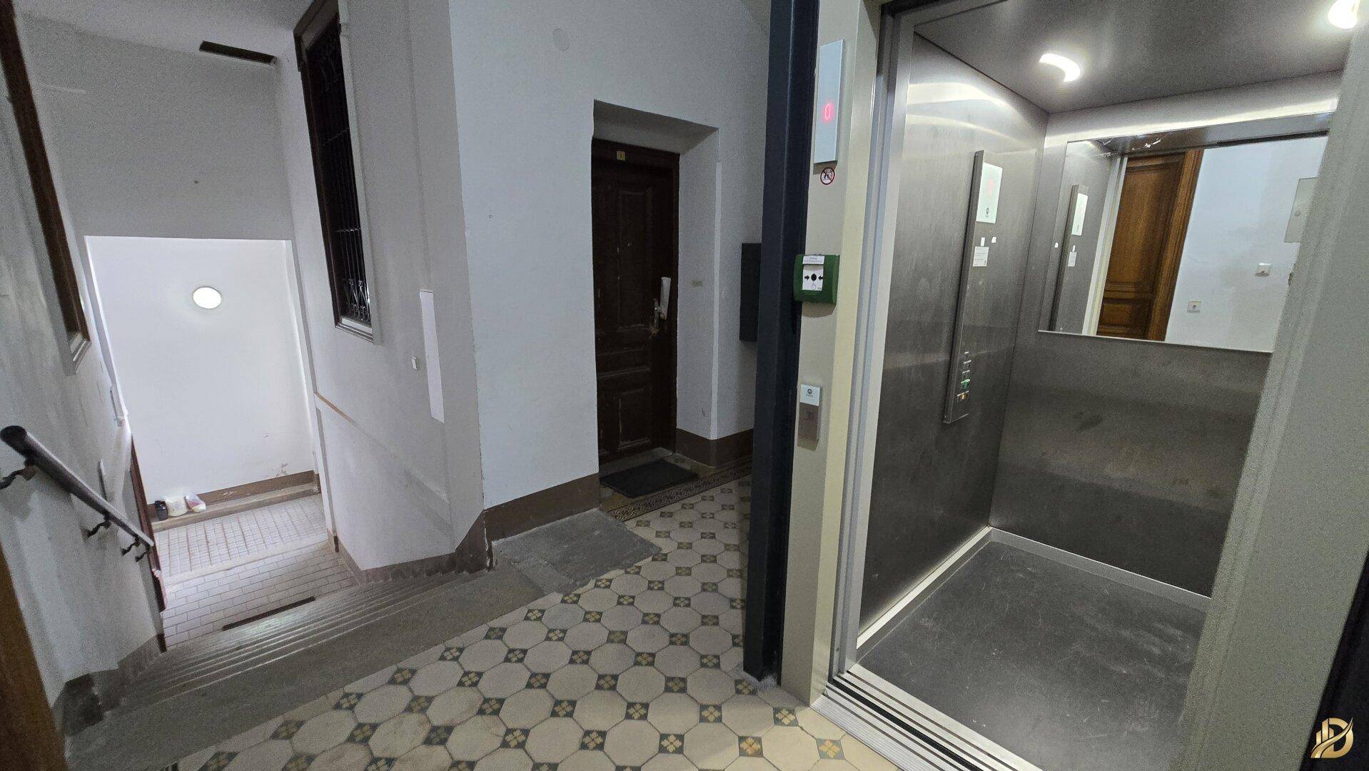 Eingangsbereich eines Gebäudes mit Treppe und modernem Aufzug für bequemen Zugang zu allen Etagen.
