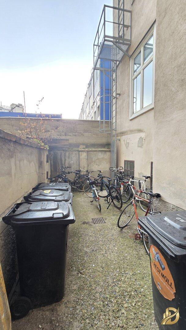 Hinterhofbereich eines Gebäudes mit Mülltonnen und Fahrradabstellplätzen, praktisch und ordentlich.