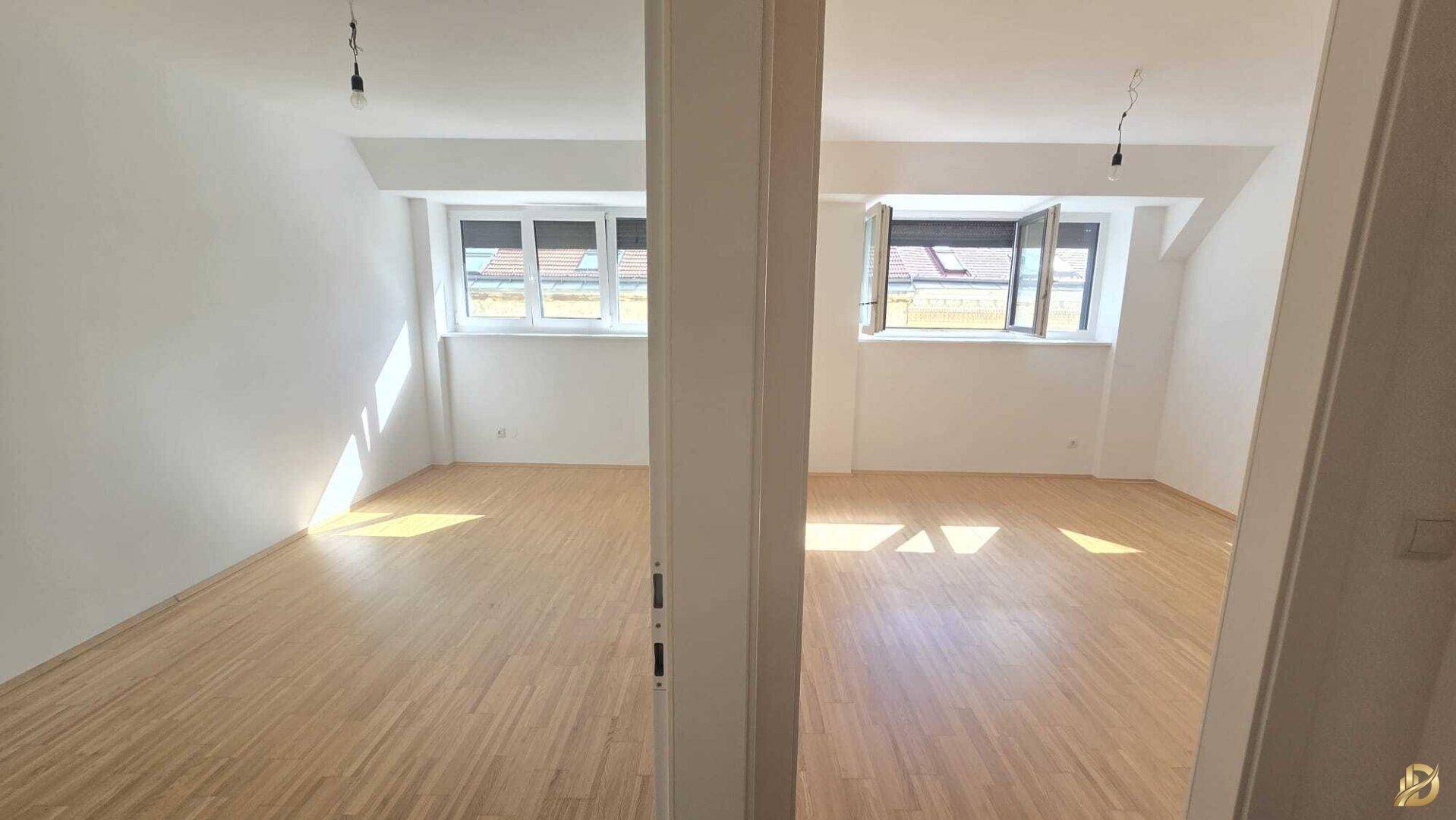 Zwei helle, leere Räume mit Holzboden und Fenstern, die viel Sonnenlicht empfangen und einladend wirken.