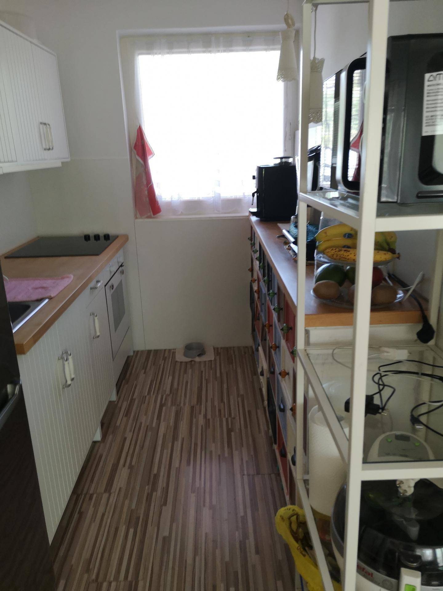 Schmale Küche mit weißen Schränken, Holz-Arbeitsplatten und einem Fenster für natürliches Licht.