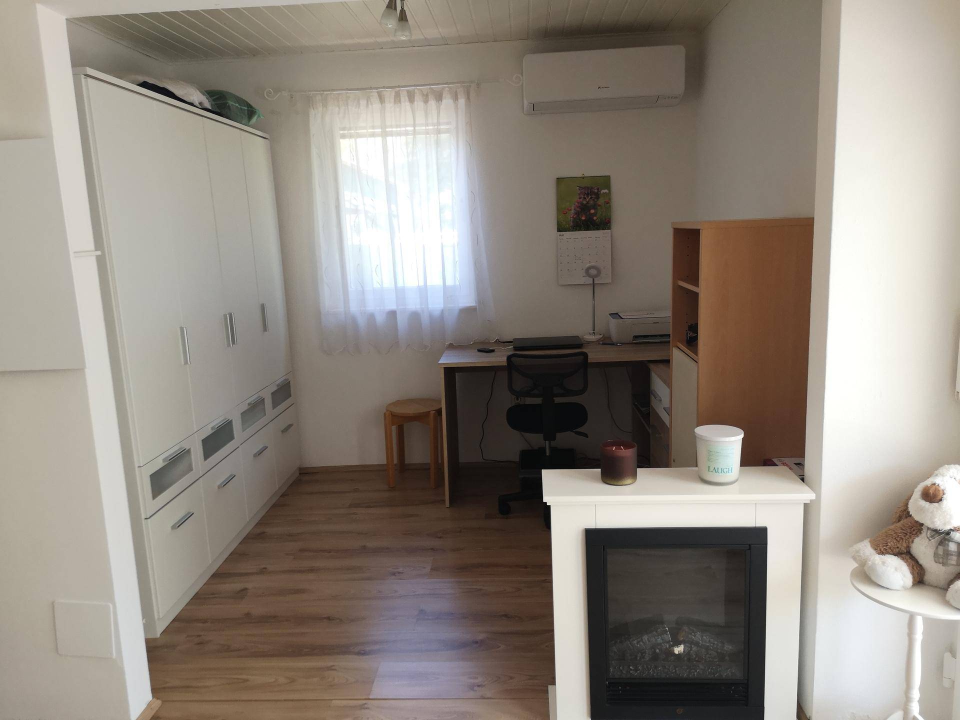 Helles Arbeitszimmer mit großem Schrank, Schreibtisch, Klimaanlage und dekorativem Kamin.