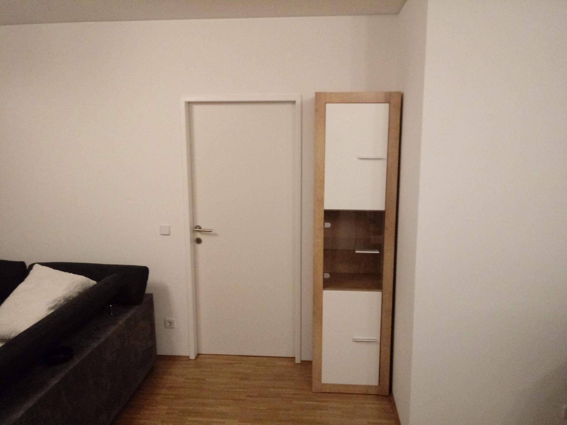 Heller Bereich mit Tür und hohem Schrank, passend zum Wohnbereich.