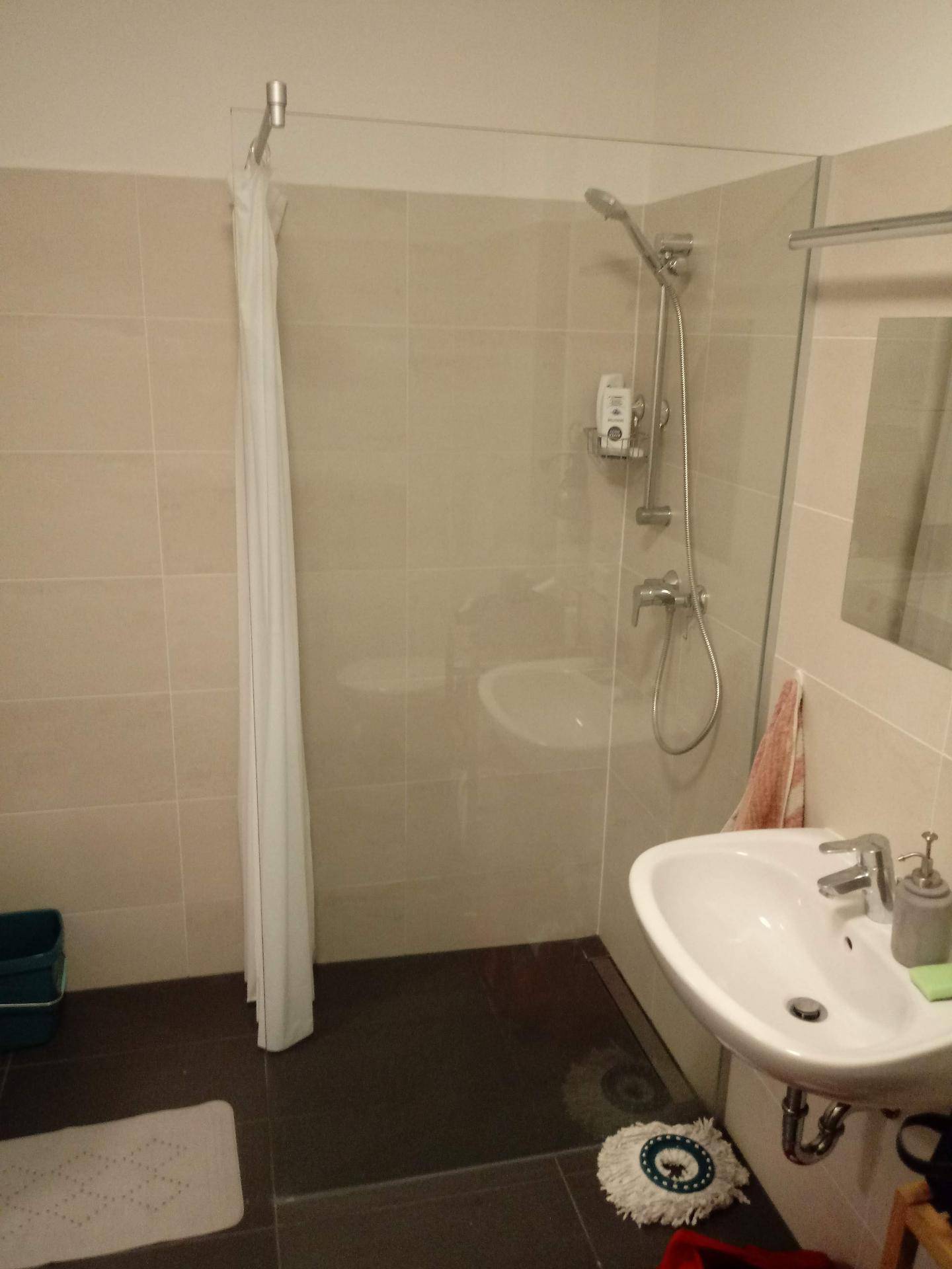 Modernes Badezimmer mit Duschkabine, Waschbecken und hellen Wandfliesen.