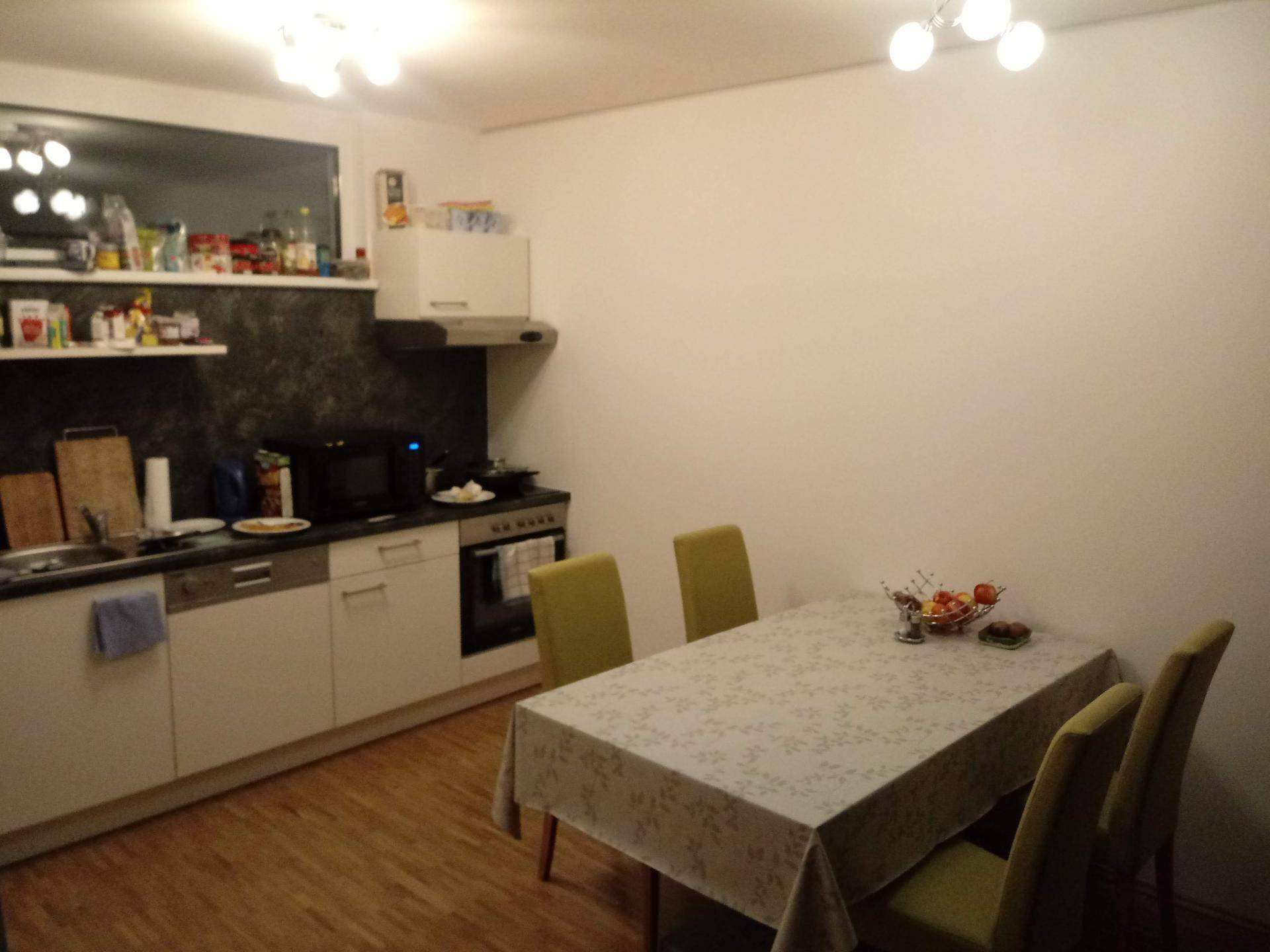 Funktionale Küche mit Essbereich, weißen Schränken und Holzboden.