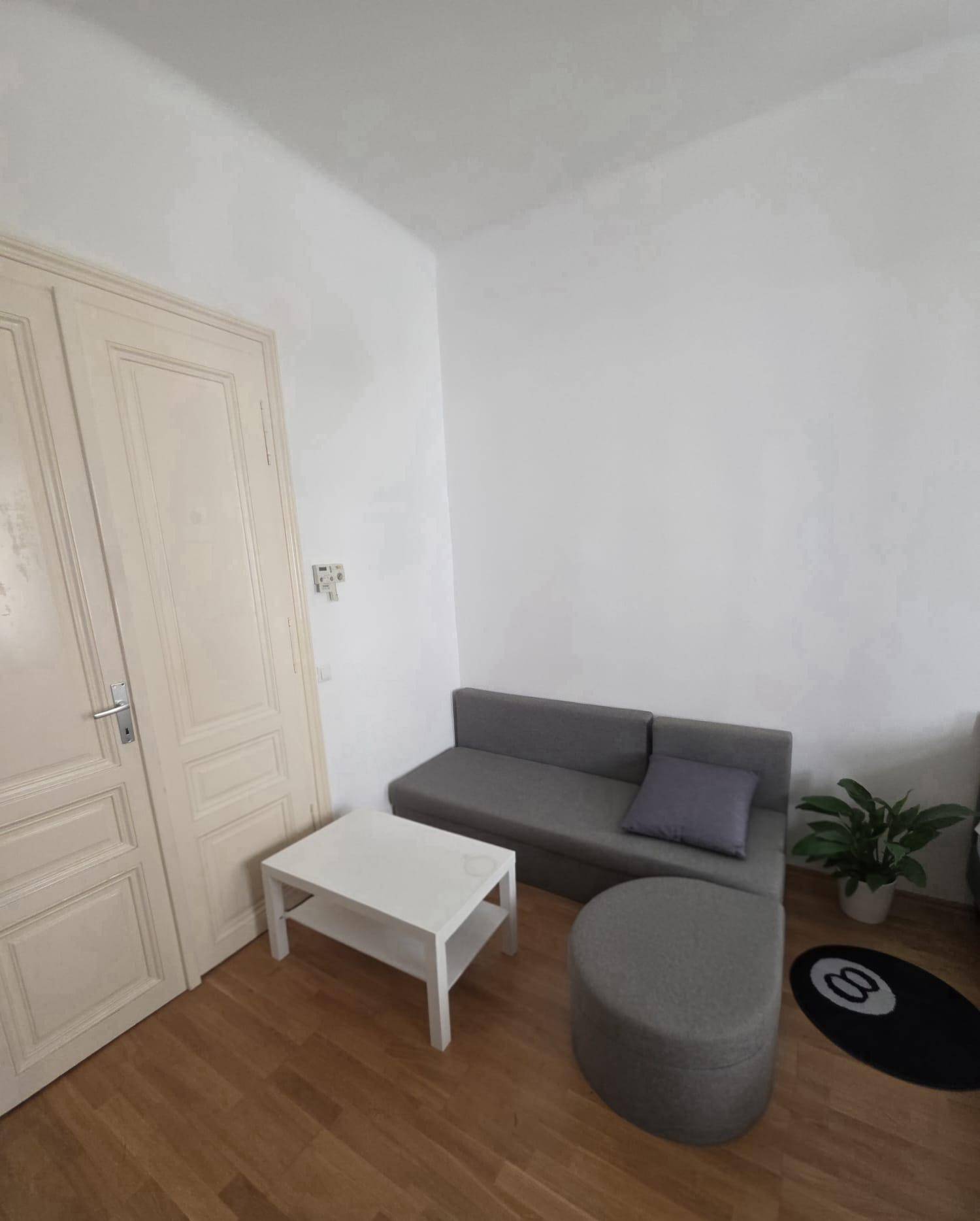 Gemütliches Wohnzimmer mit grauem Sofa, Couchtisch und Holzboden.