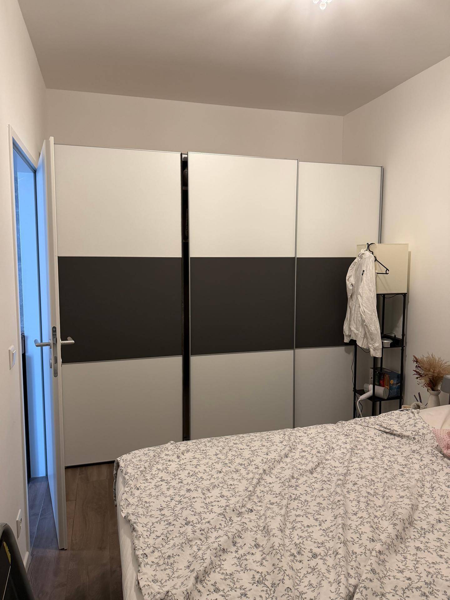 Schlafzimmer mit geräumigem Kleiderschrank in Weiß und Anthrazit, der viel Stauraum bietet.