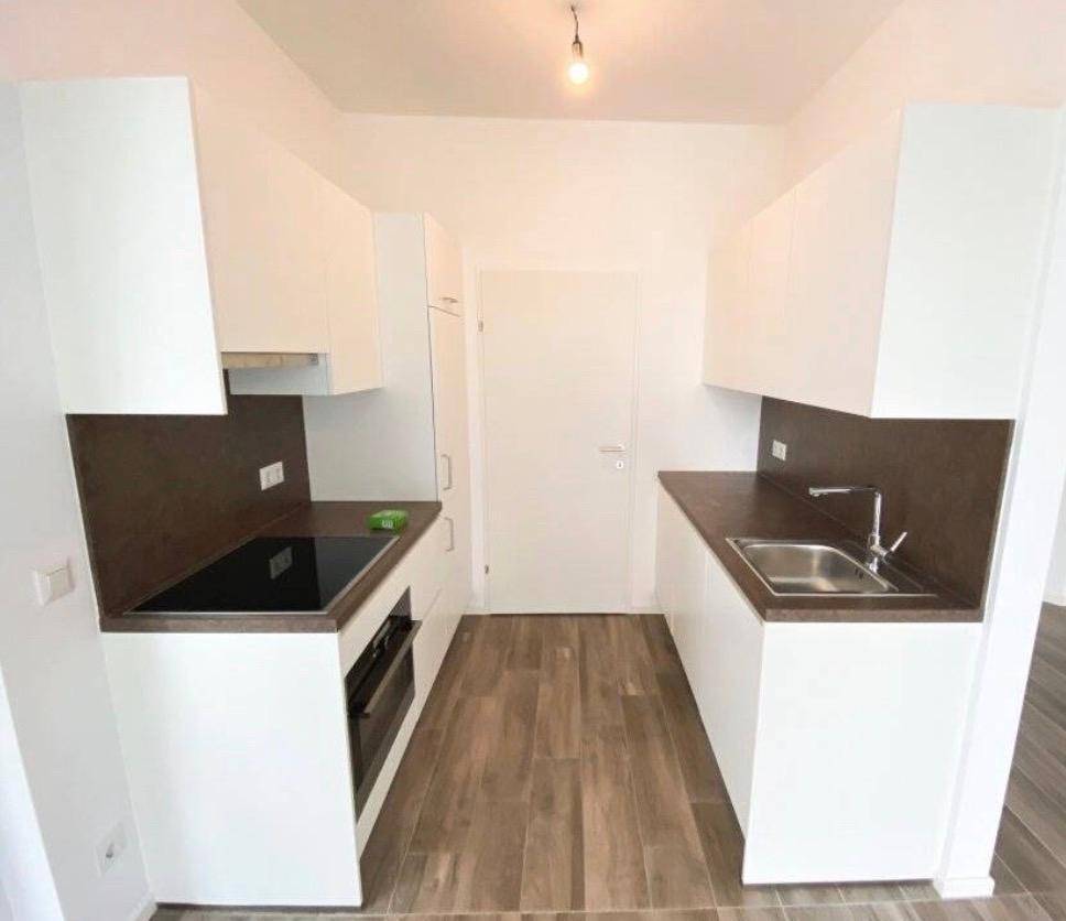 Funktionale Küche mit weißen Schränken, dunklen Arbeitsplatten und modernen Einbaugeräten.