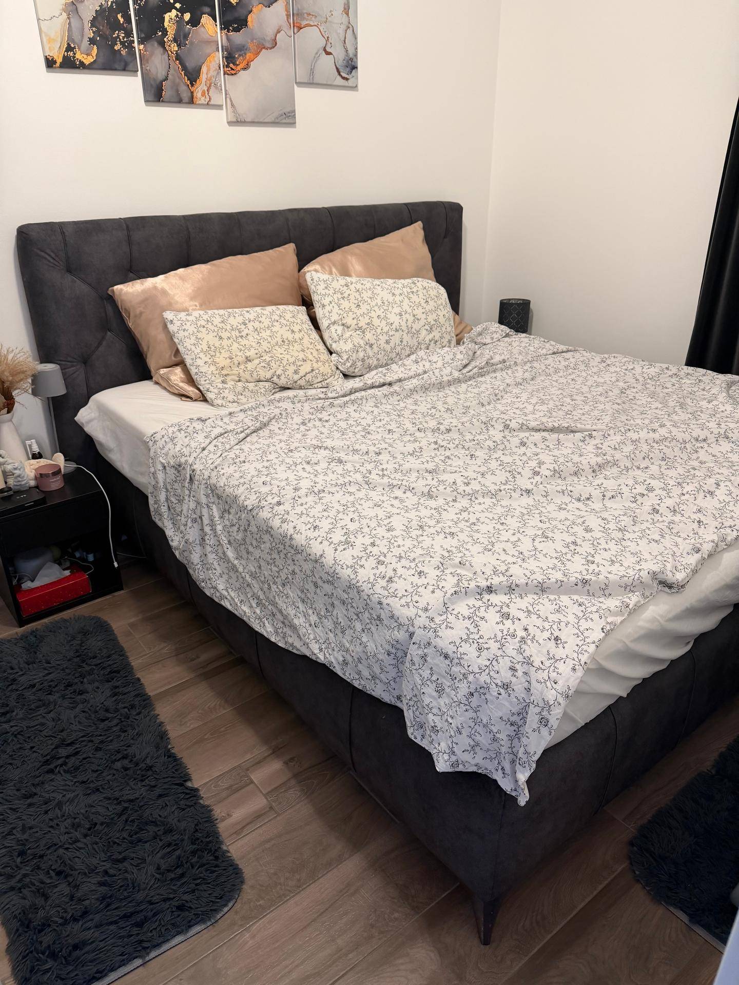 Schlafzimmer mit großem, gepolstertem Doppelbett, dunklem Kopfteil und moderner Wanddekoration.