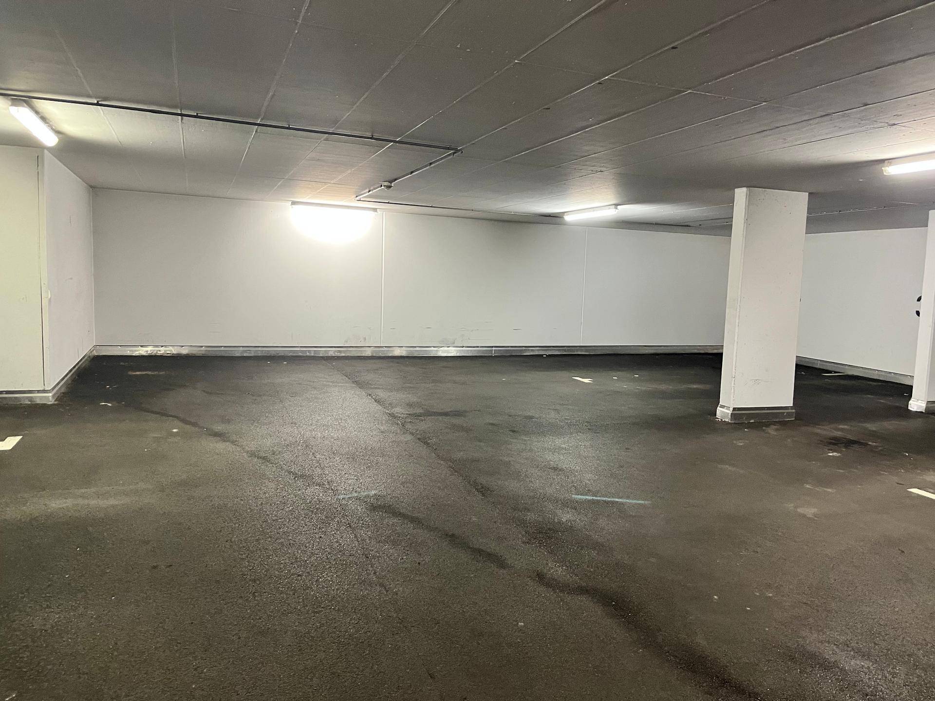 Geräumige Tiefgarage mit mehreren leeren Stellplätzen und Säulen.