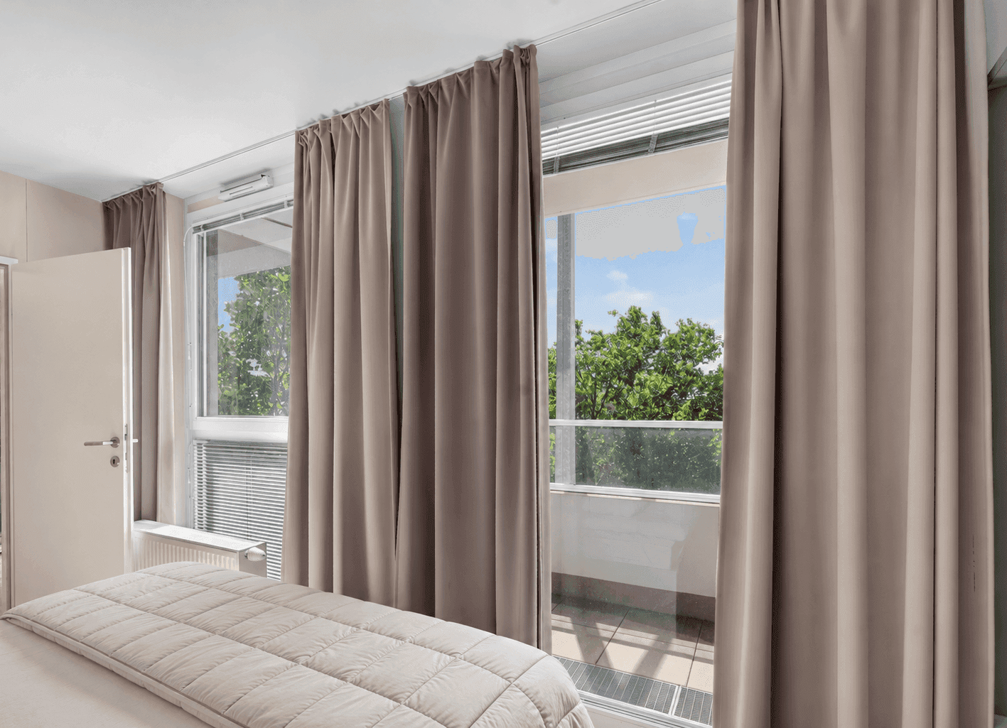 Schlafzimmer mit Balkonzugang, Doppelbett und Blick ins Grüne.