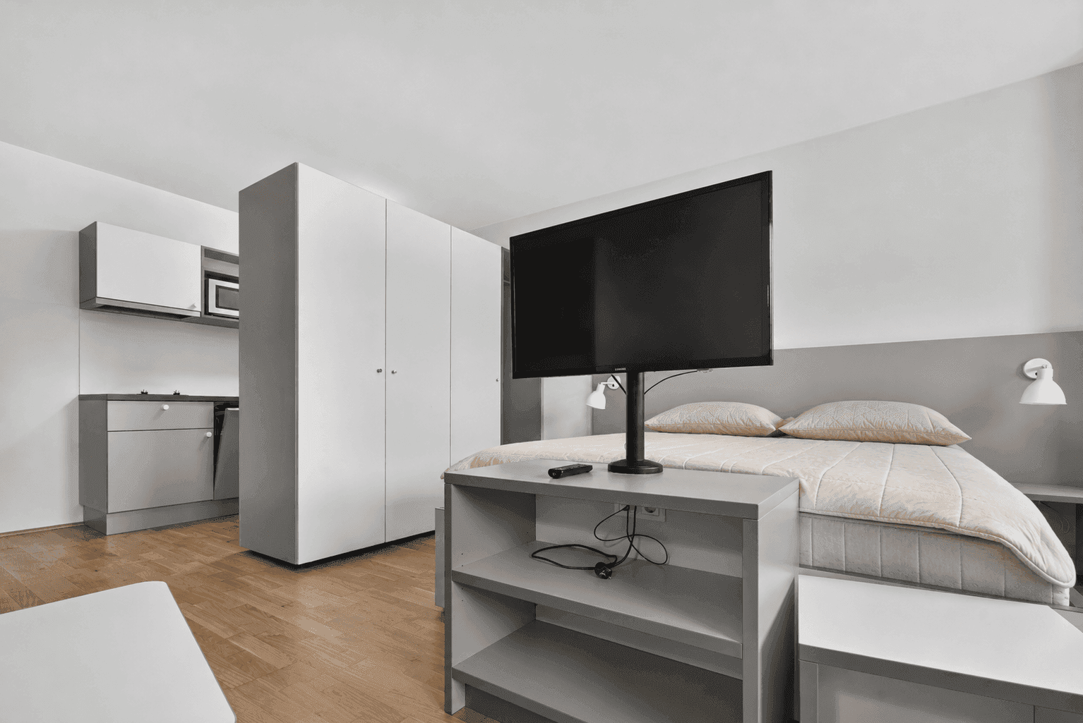 Schlafbereich eines Studio-Apartments mit integrierter Küchenzeile und Kleiderschrank.