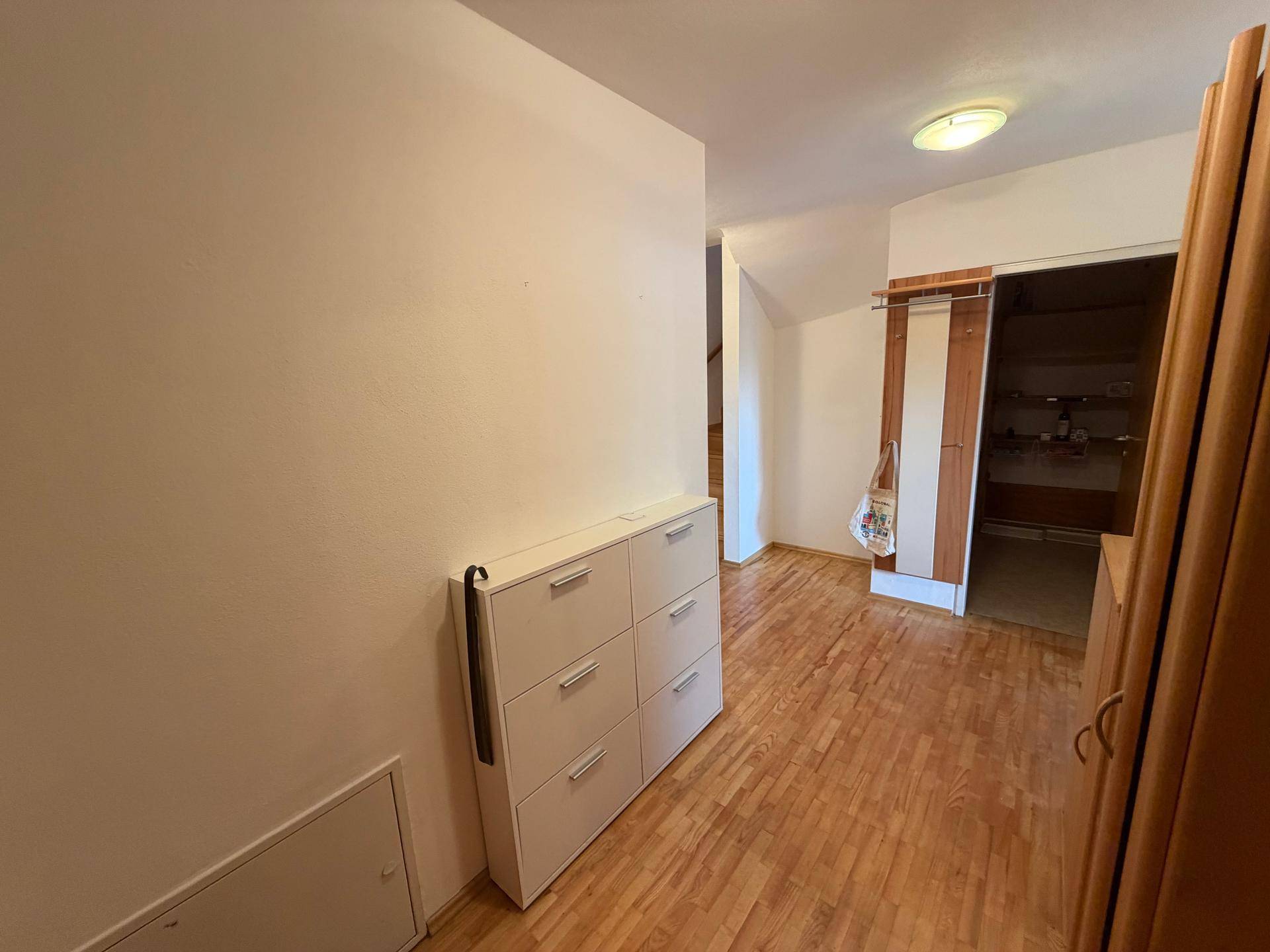 Heller Flur mit Holzfußboden und einem praktischen Schuhschrank an der Wand.