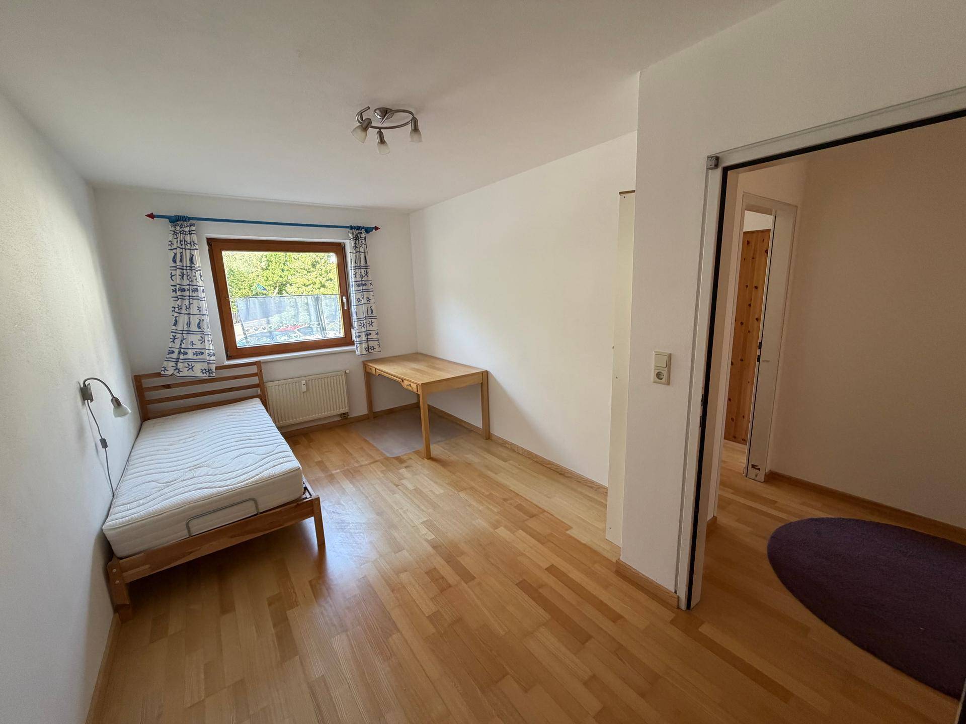 Gemütliches Schlafzimmer mit Einzelbett, Schreibtisch und hellem Holzfußboden.