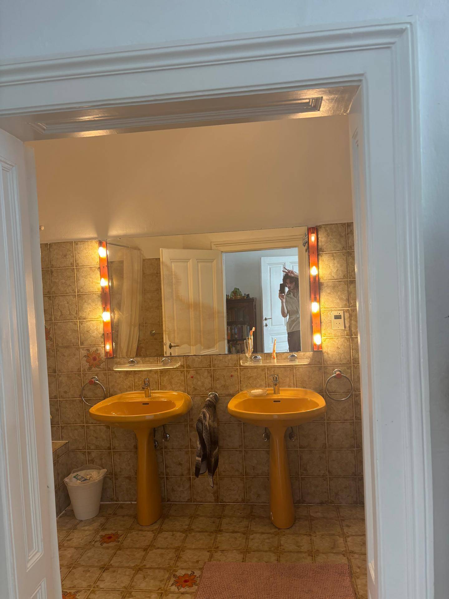 Badezimmer mit zwei gelben Waschbecken, Fliesen und Spiegelschrank.