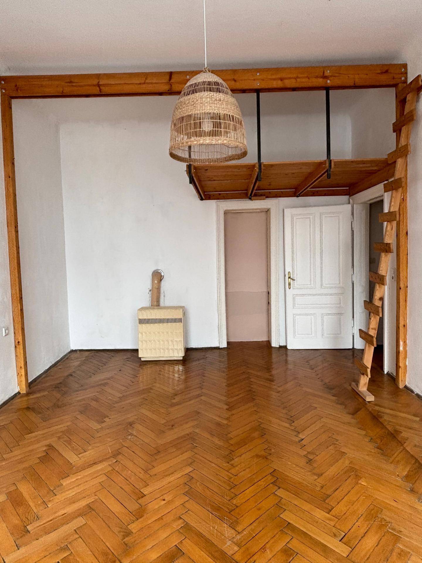 Leeres Zimmer mit Fischgrätparkett und einer Holzkonstruktion für ein Hochbett.