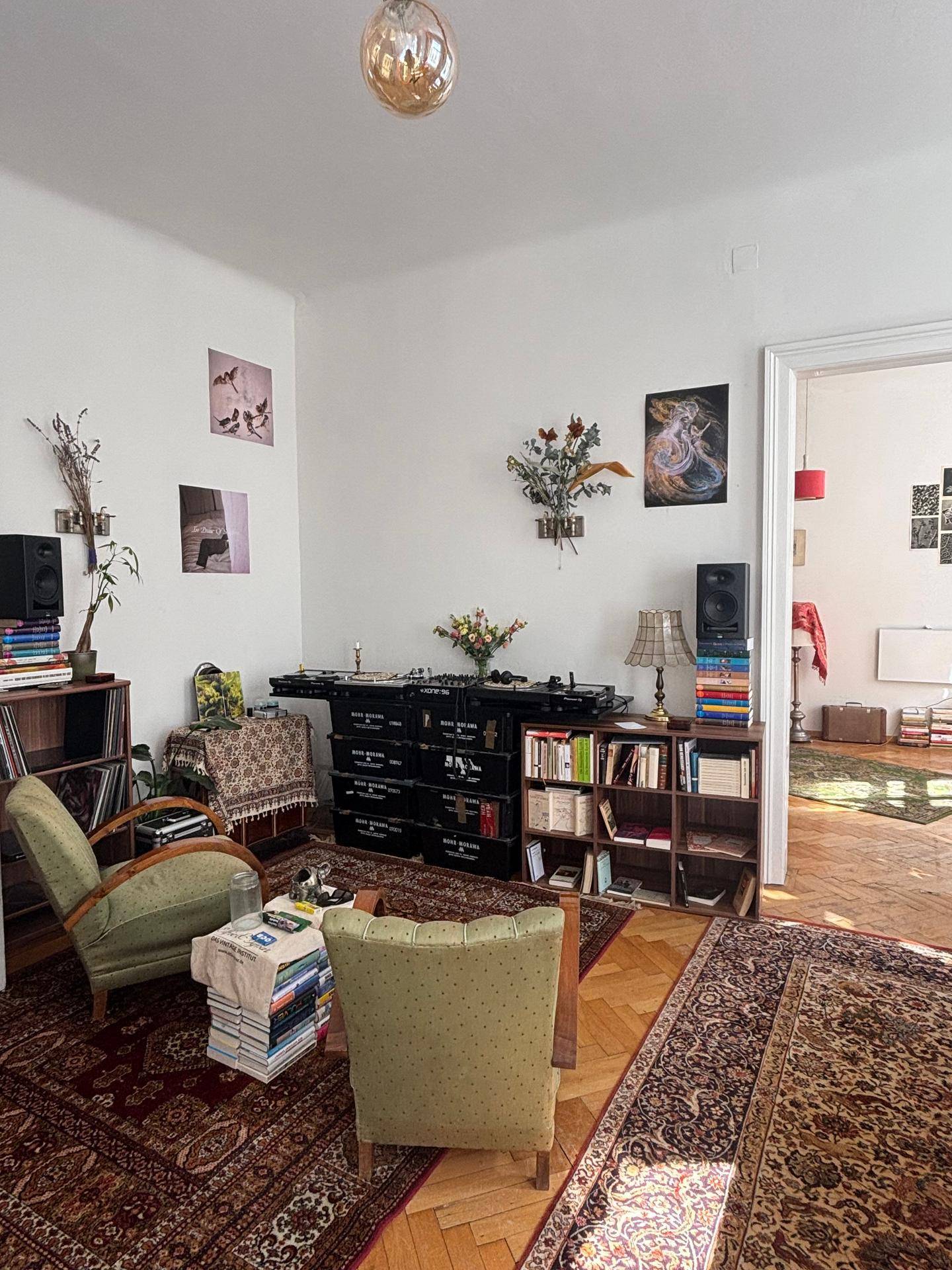 Gemütliches Wohnzimmer mit Teppichen, Sesseln und Bücherregalen.