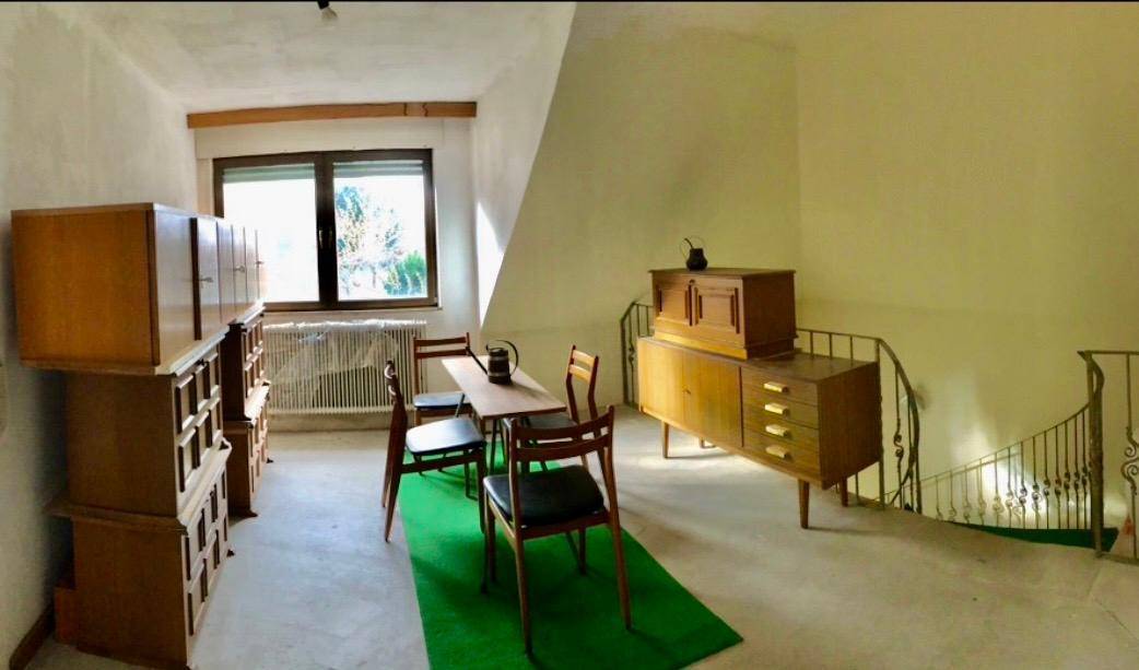 Dachgeschossraum mit schrägen Decken, Vintage-Möbeln und einer geschwungenen Treppe.