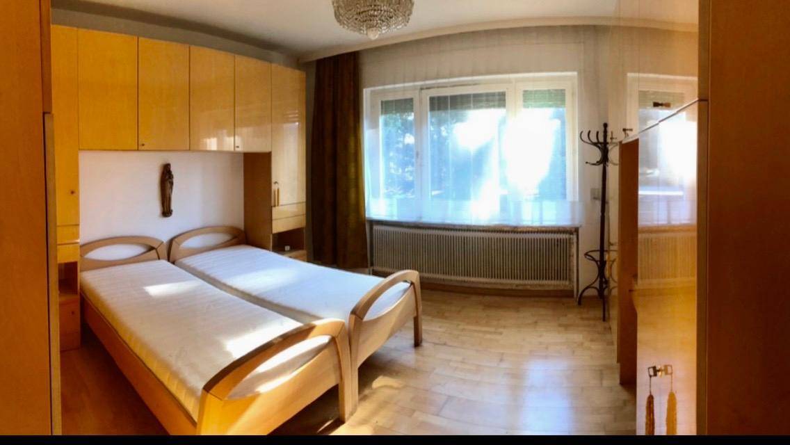 Schlafzimmer mit zwei Einzelbetten, Einbauschränken aus Holz und viel Tageslicht.