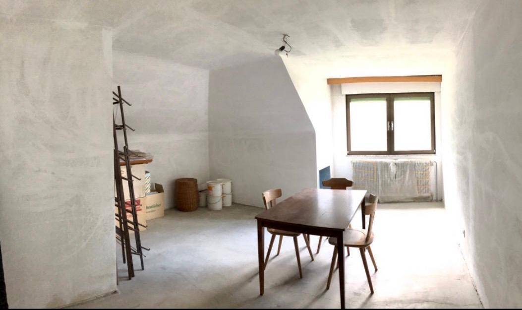 Heller Dachgeschossraum mit schrägen Decken, einem Tisch und Stühlen.