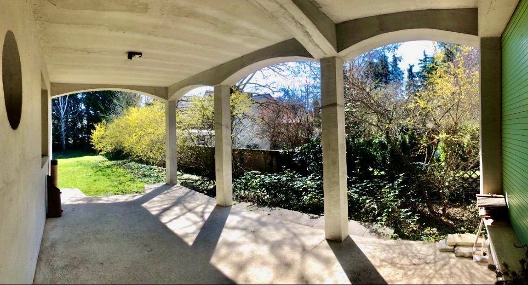 Überdachte Loggia mit Bögen und Blick auf den grünen Gartenbereich.