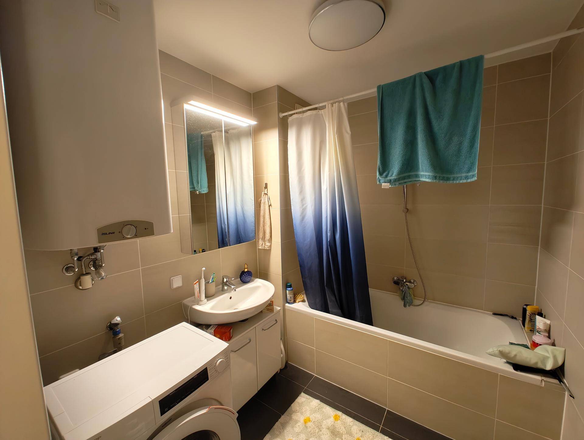 Modernes Badezimmer mit Badewanne, Duschvorhang, Waschbecken und Waschmaschine.