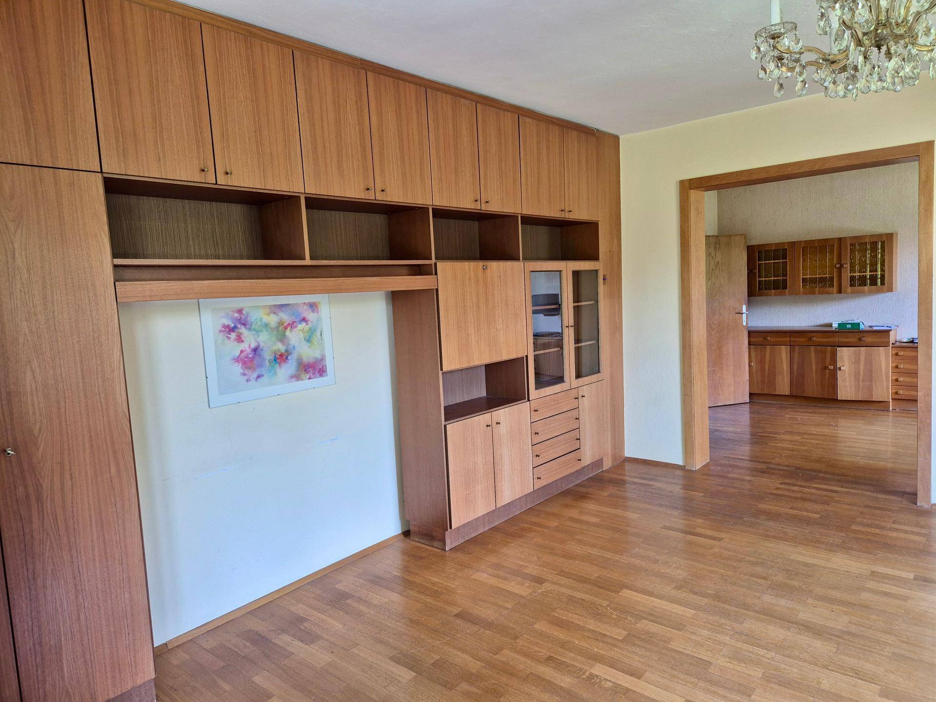 Wohnraum mit umfangreichen Holz-Einbauschränken und Durchgang zu einem weiteren Zimmer.