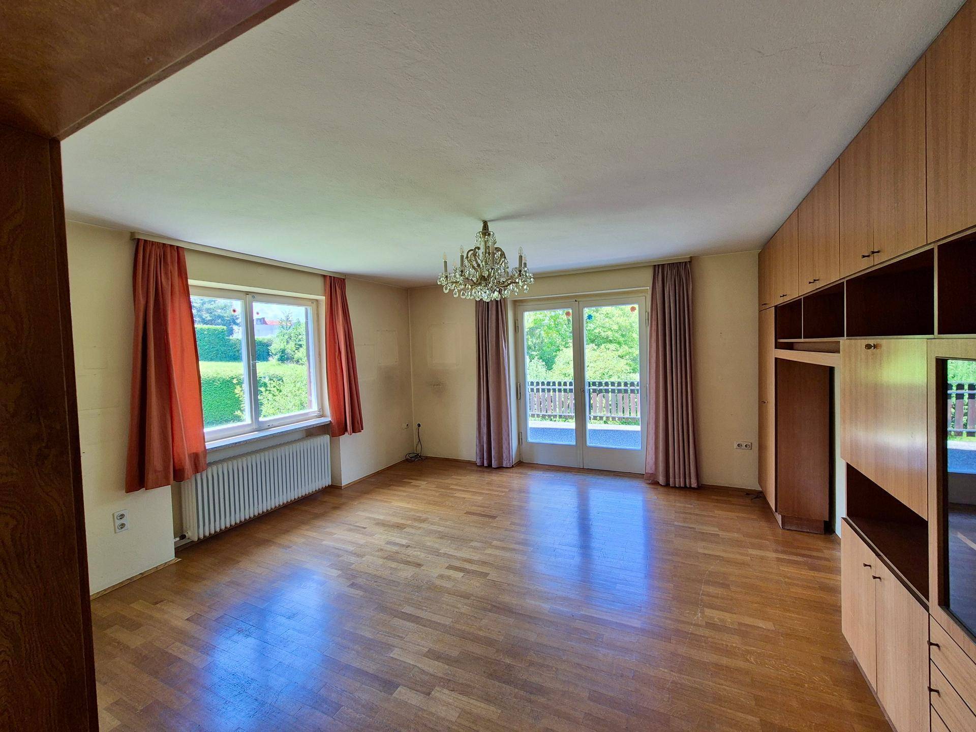 Geräumiges Wohnzimmer mit Parkettboden, Einbauschränken und direktem Zugang zum Balkon.
