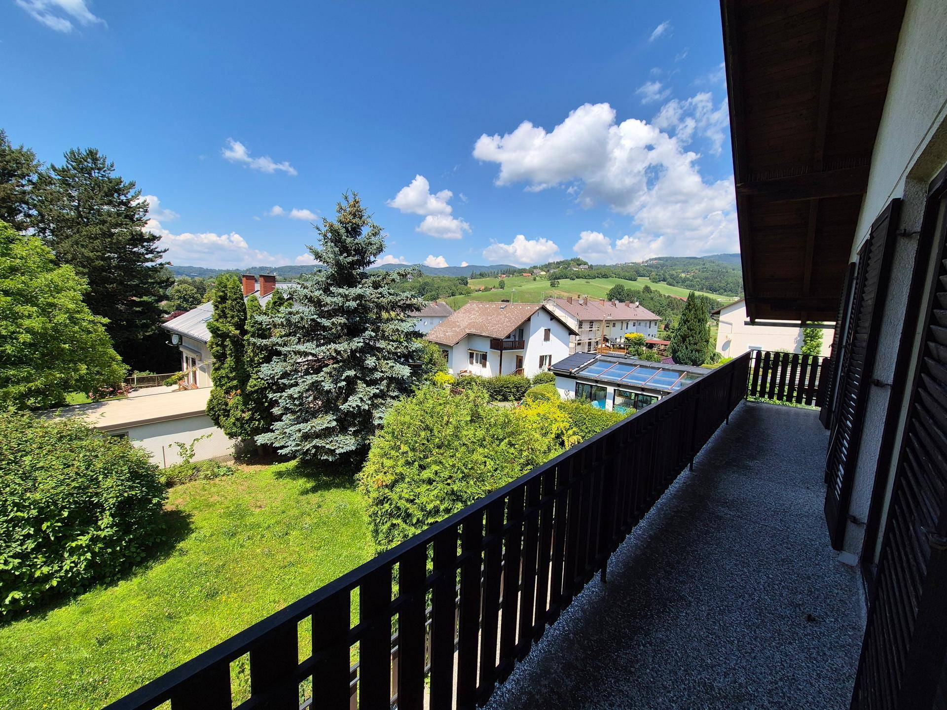 Langer Balkon mit weitem Blick über die umliegende Wohnsiedlung und grüne Landschaft.
