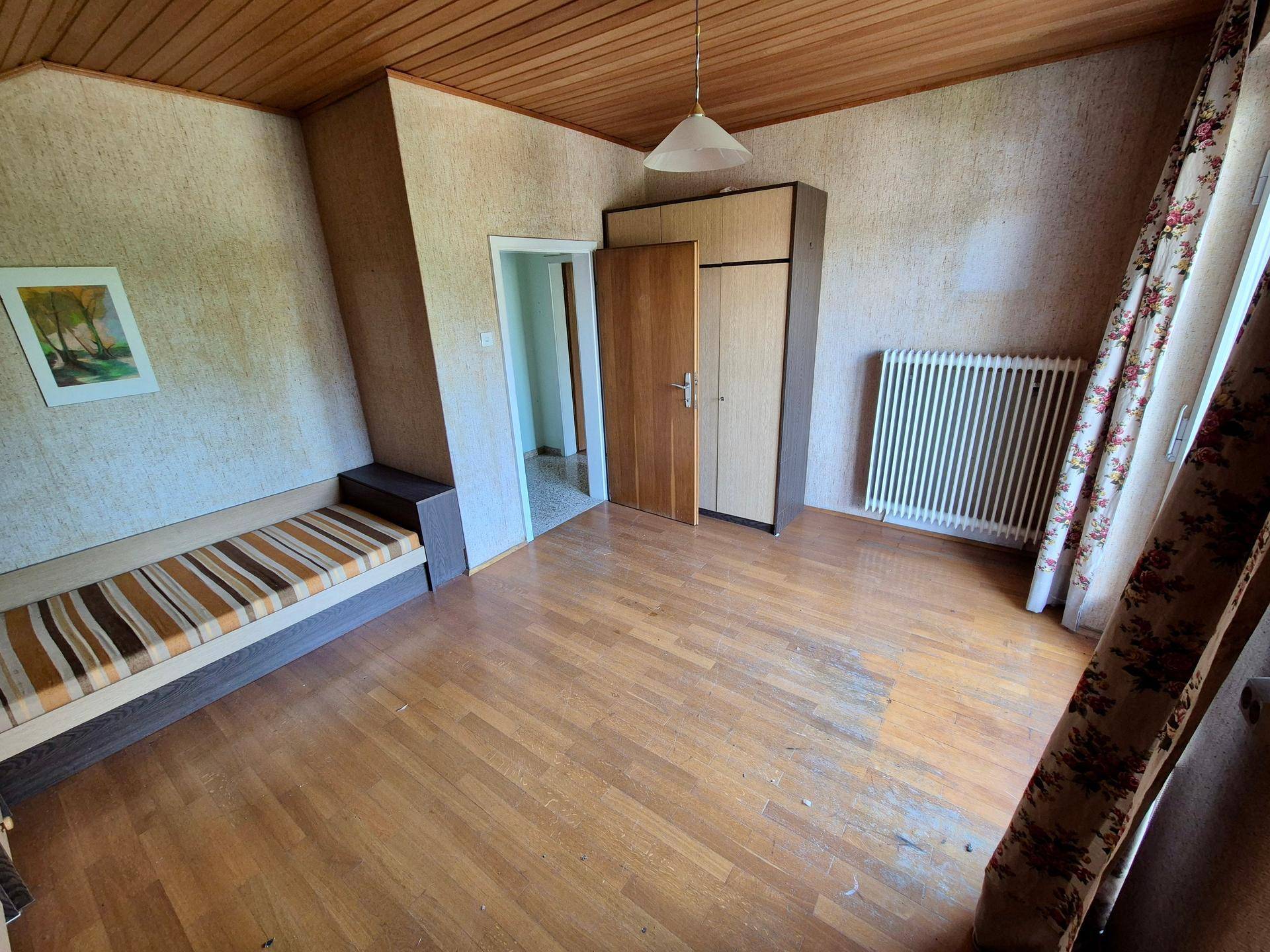 Gemütliches Schlafzimmer mit Parkettboden, Holzdecke und Tagesbett unter Dachschräge.