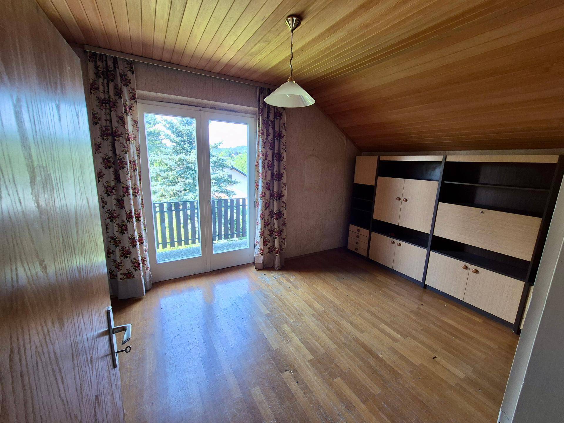Schlafzimmer mit Parkettboden, Holzdecke, Einbauschränken und Balkonzugang unter Dachschräge.