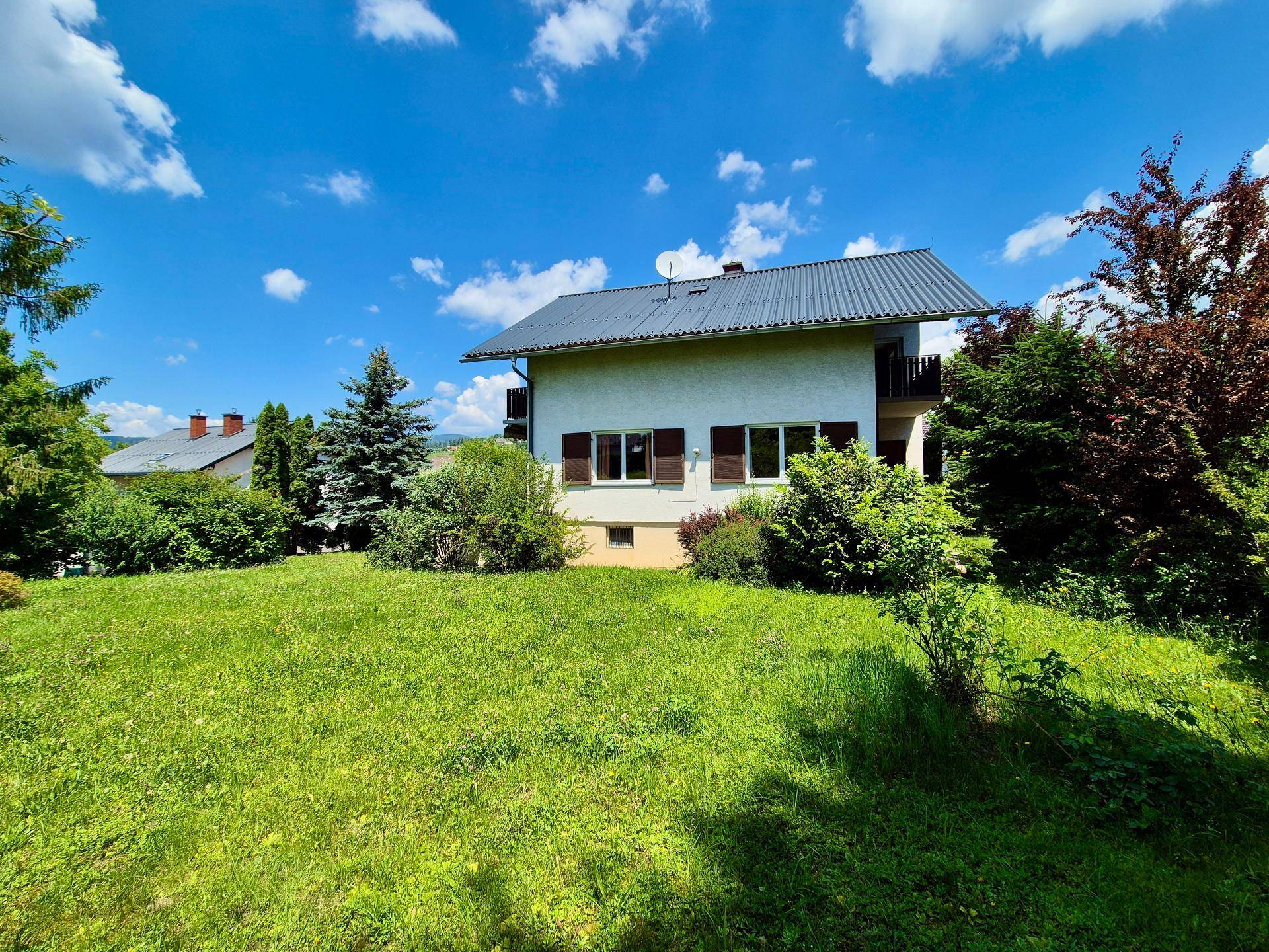 Rückansicht des Hauses mit großem, gepflegtem Rasen und Blick auf die umliegende Landschaft.