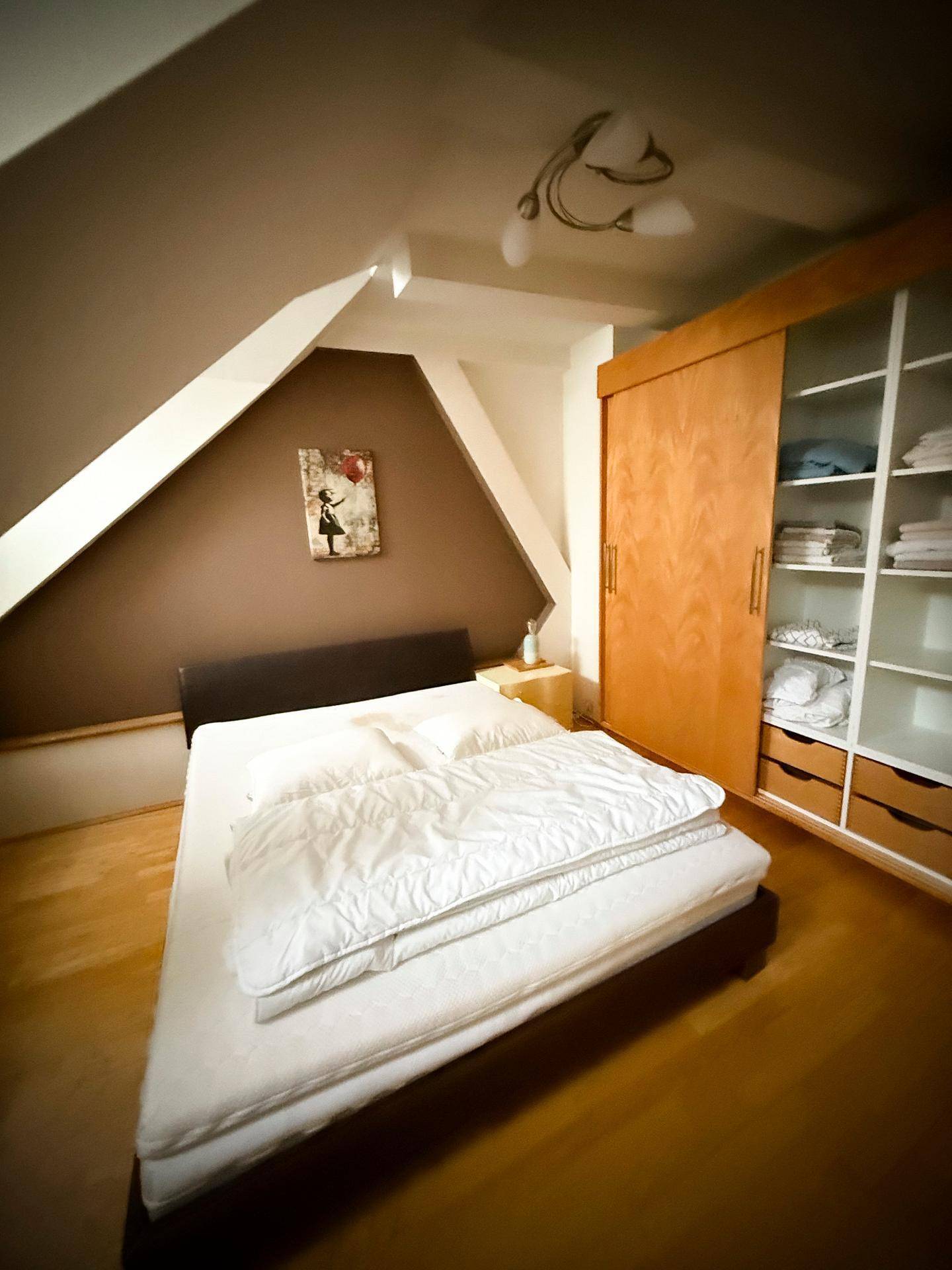 Gemütliches Schlafzimmer mit Doppelbett, Einbauschrank und charakteristischen Dachschrägen.