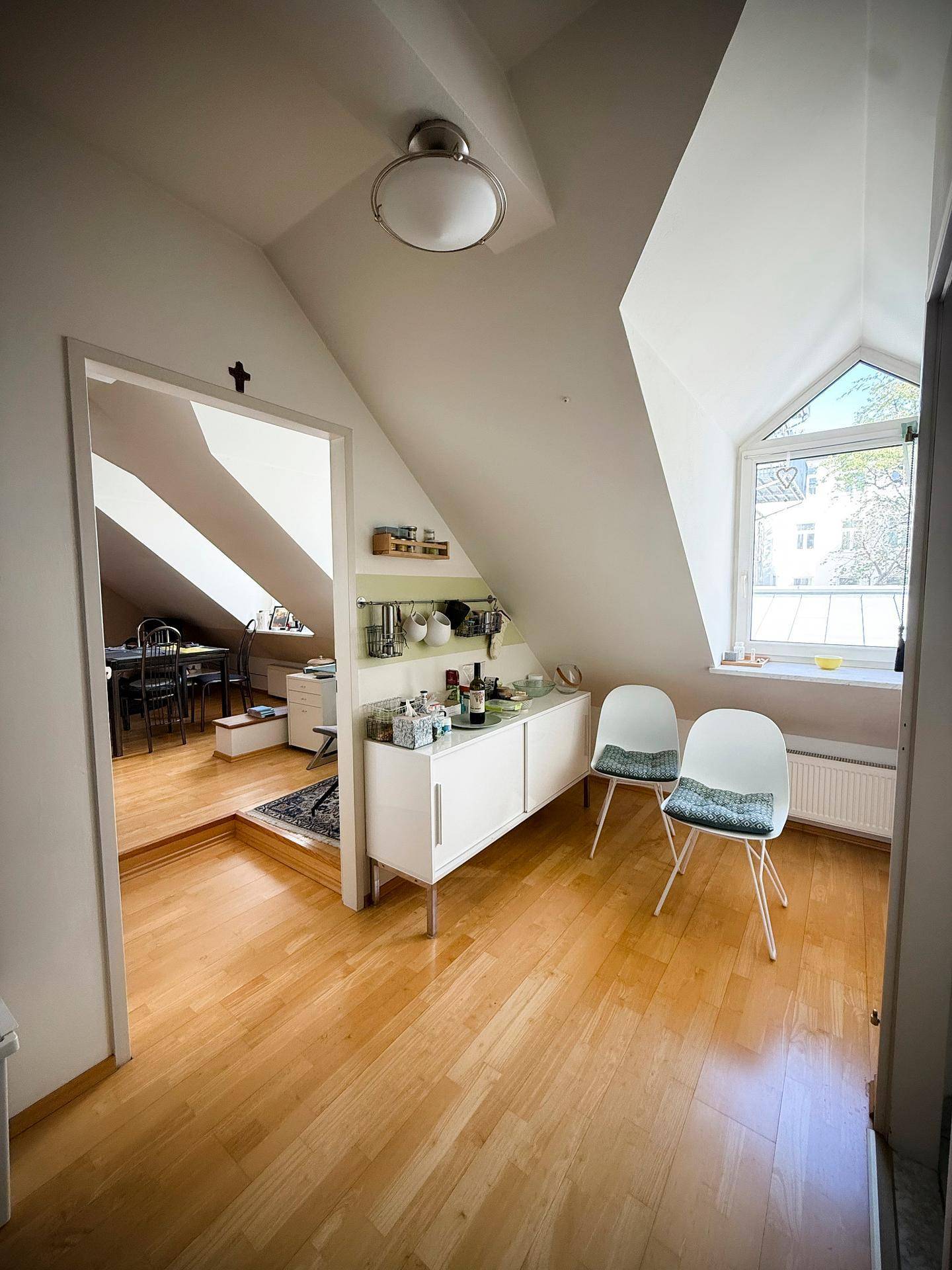 Heller Flurbereich mit Holzfußboden und Dachschrägen, der zu einem weiteren Zimmer führt.
