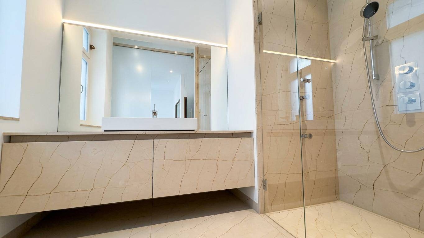 Elegantes Badezimmer mit großem Waschtisch, Einzelwaschbecken und geräumiger begehbarer Dusche.