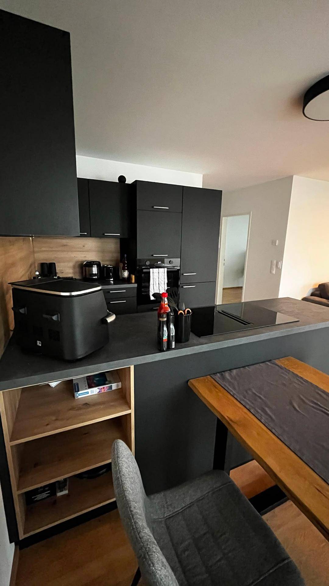 Moderne schwarze Küche mit Kochinsel und integriertem Essbereich, ideal für geselliges Kochen.