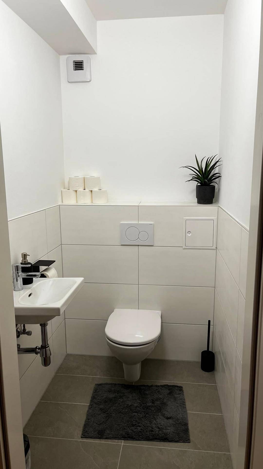 Kleines Gäste-WC mit wandhängender Toilette und Handwaschbecken, sauber und funktional gestaltet.