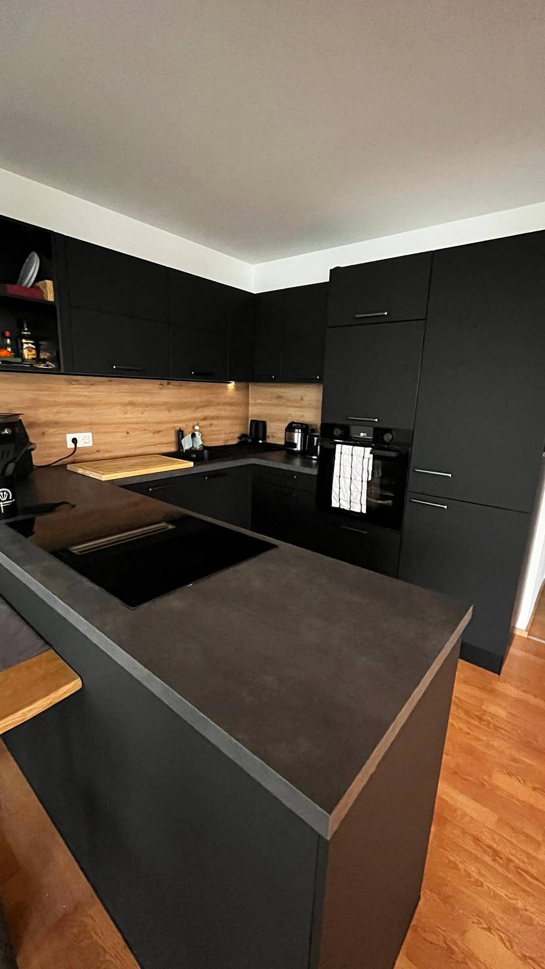 Elegante schwarze Einbauküche mit Kochinsel und modernen Geräten, bietet viel Arbeitsfläche.