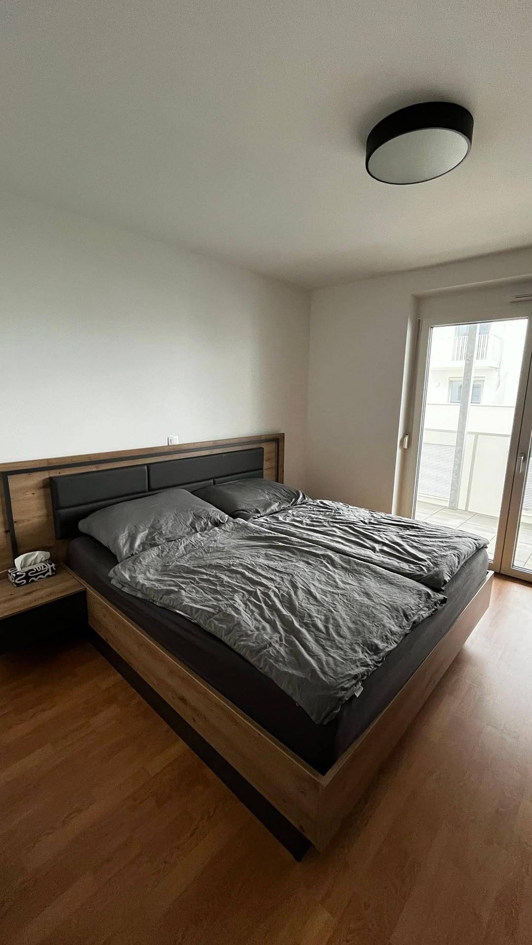 Gemütliches Schlafzimmer mit Doppelbett, Holzboden und direktem Zugang zum Balkon, hell und einladend.