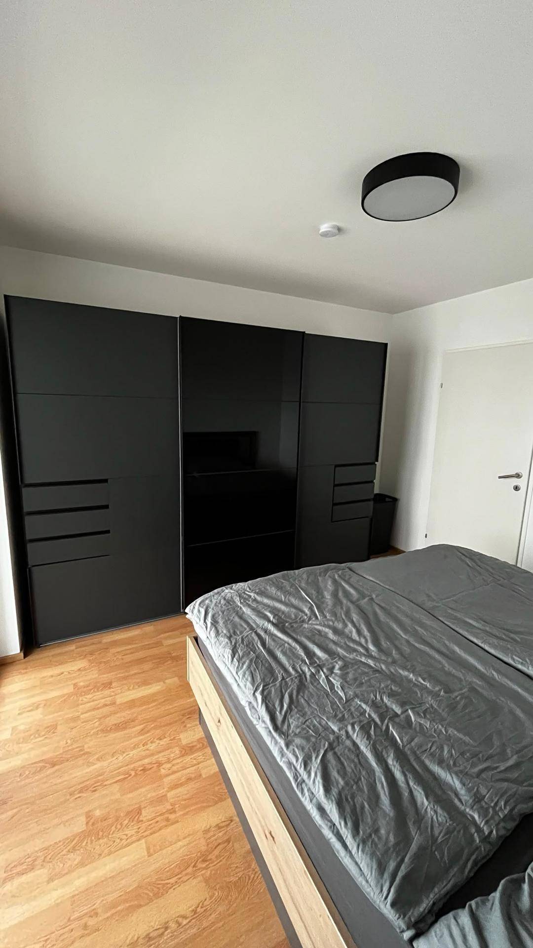 Geräumiges Schlafzimmer mit modernem schwarzen Kleiderschrank und bequemen Doppelbett, ideal für Erholung.
