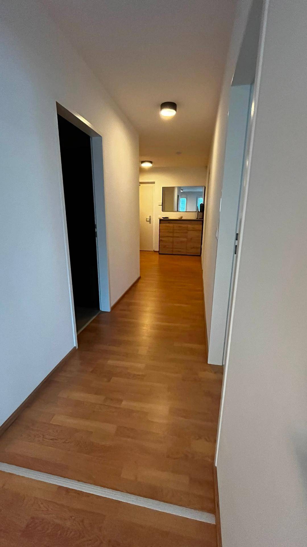 Langer Flur mit Holzboden, der zu den verschiedenen Räumen der Wohnung führt.