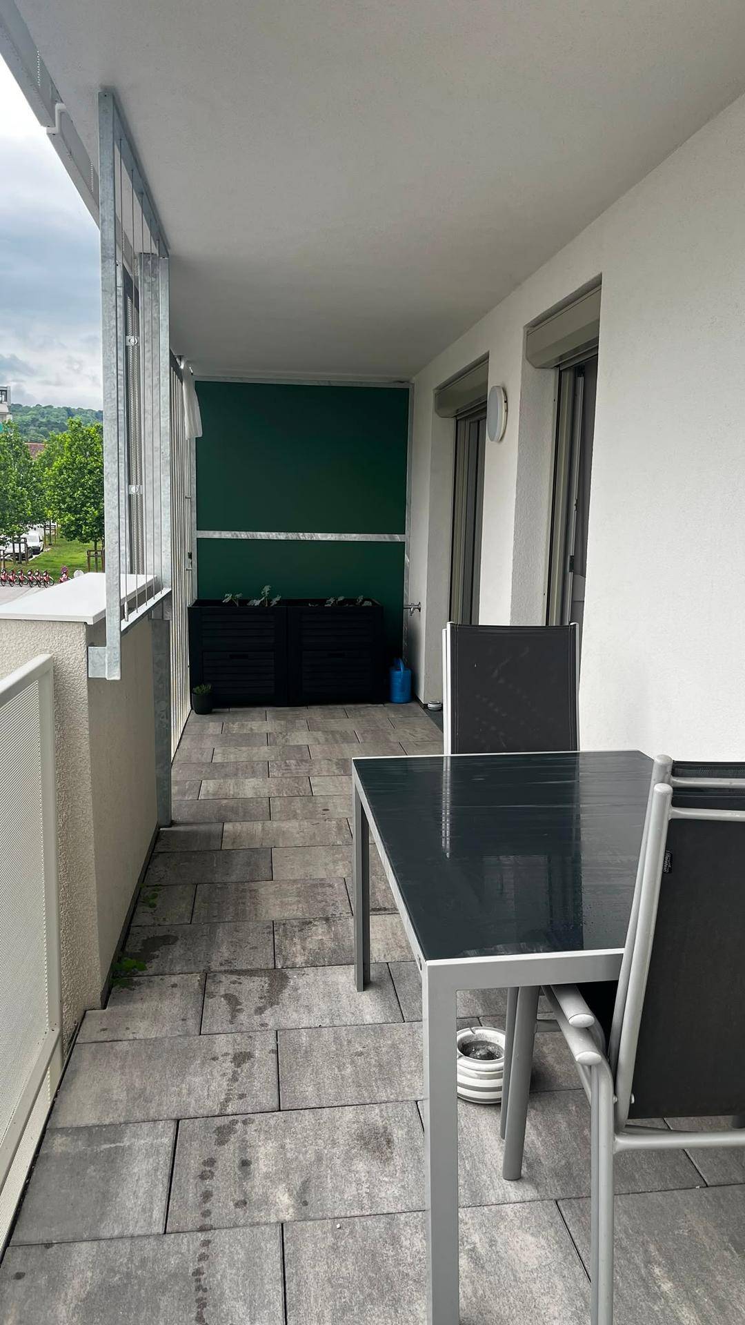 Geräumiger Balkon mit Outdoor-Möbeln und Blick ins Grüne, ideal zum Entspannen im Freien.